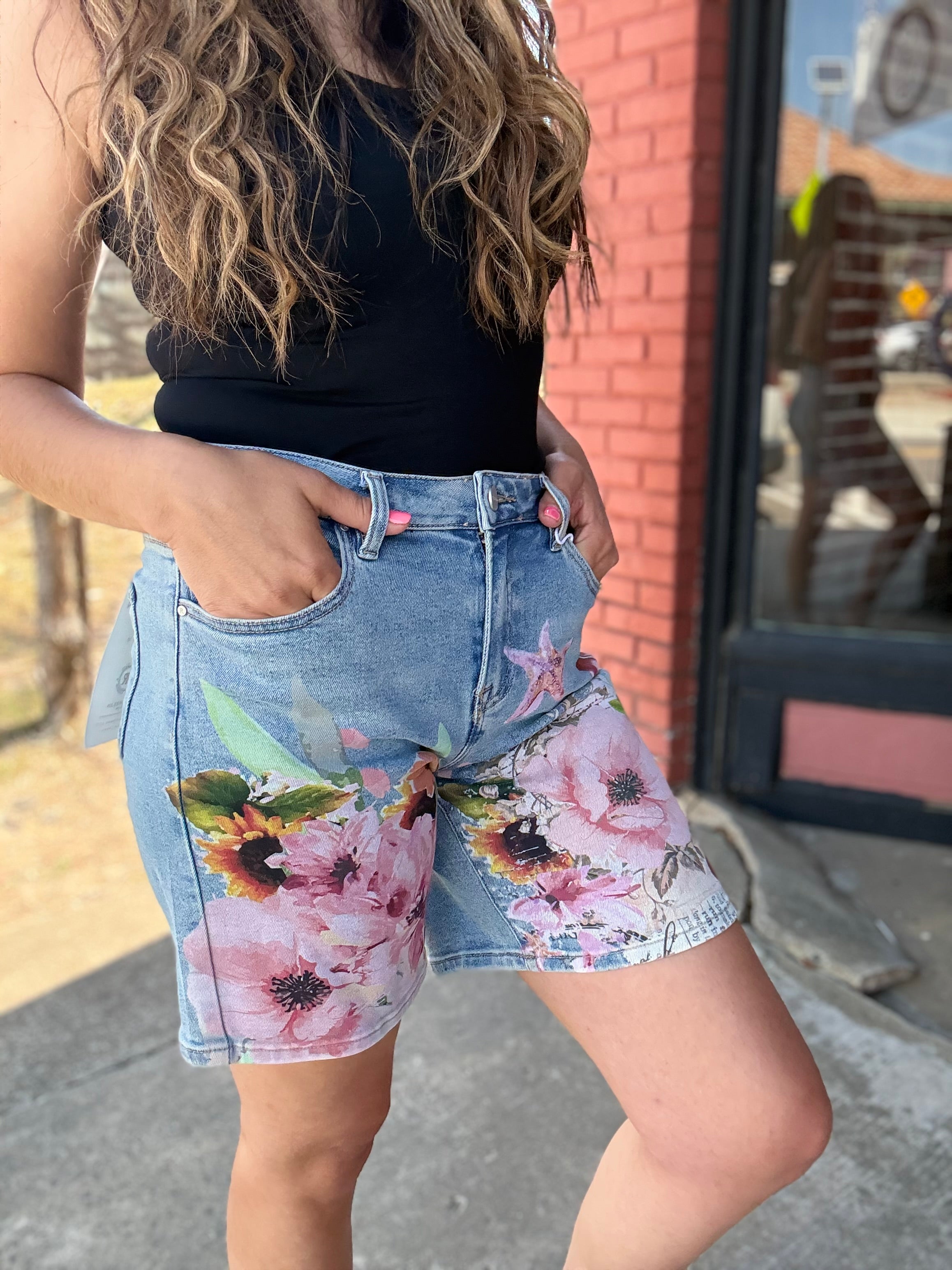 Person wearing floral denim shorts with a blurred background