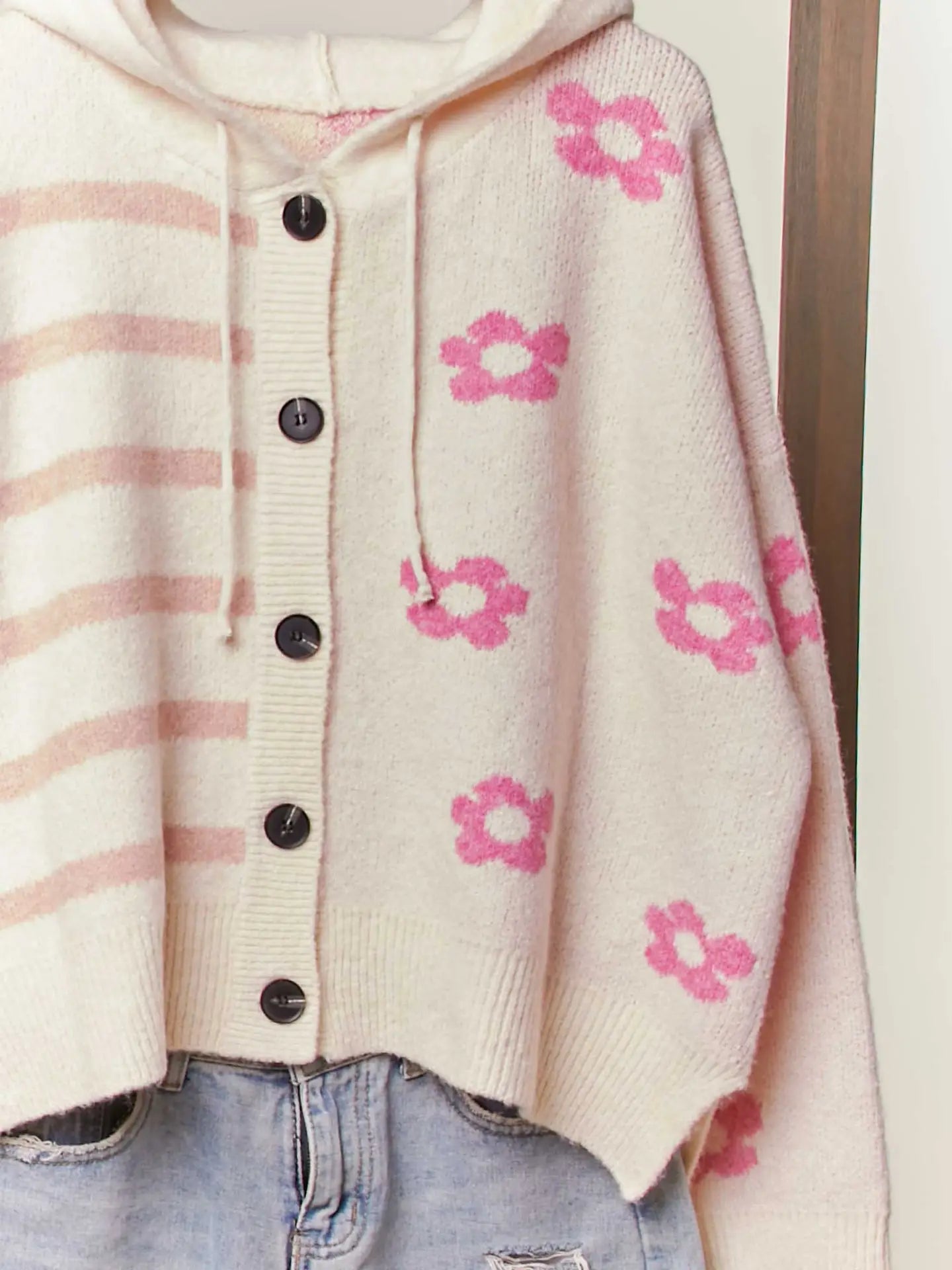 Cardigan with pink floral patterns and striped sleeves on a neutral background