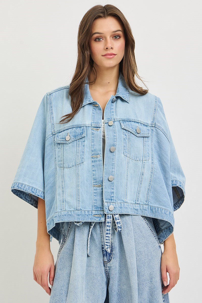Woman wearing a light blue denim jacket on a plain background