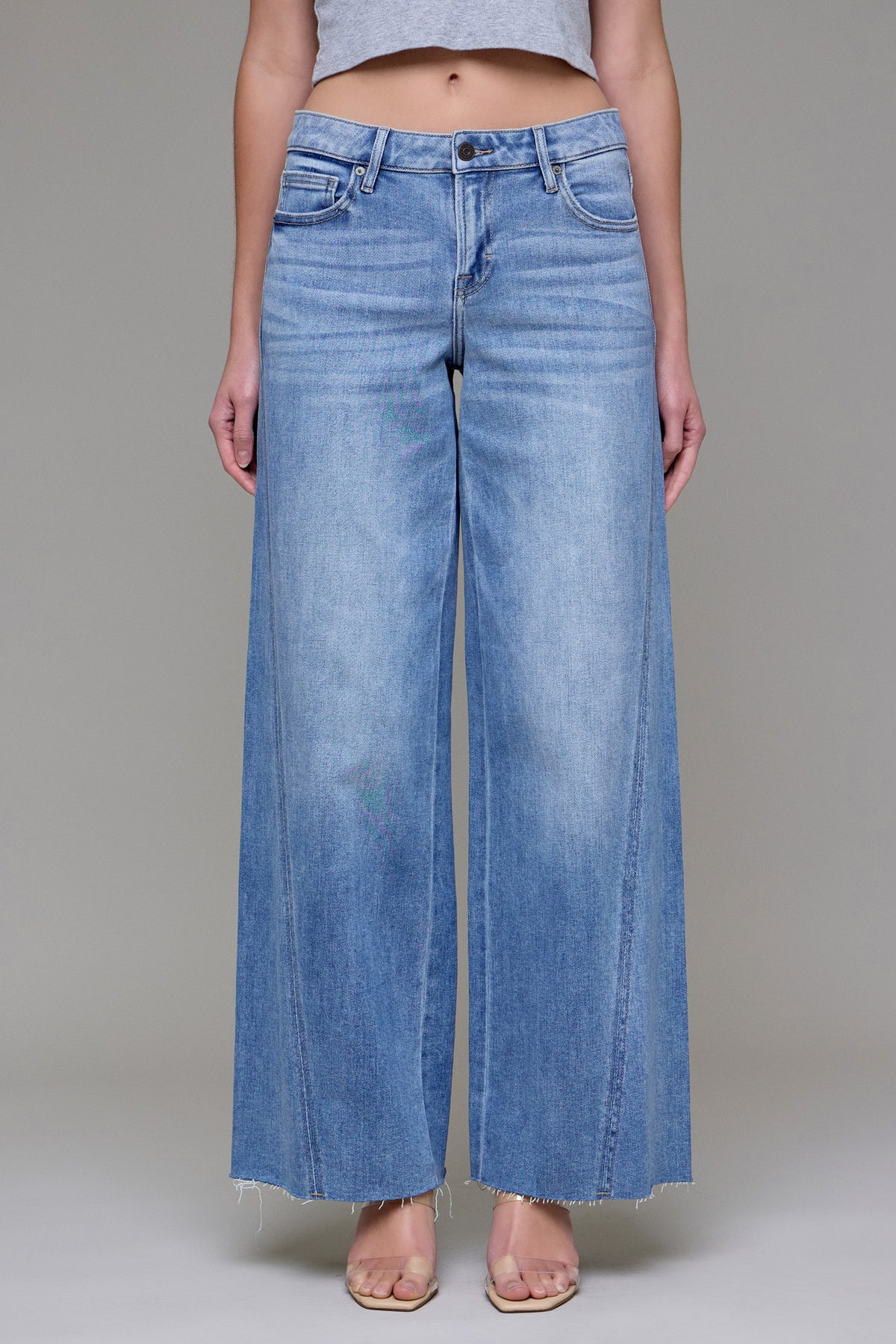 Front view of a model wearing Easygoing Edge medium-light wash wide-leg jeans with faded detailing, forward seams, and raw hems.
