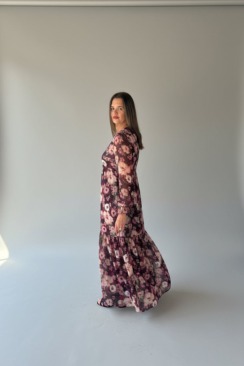 Burgundy floral long-sleeve maxi dress with tiered hem, side view showing flowing silhouette and ruffle cuffs