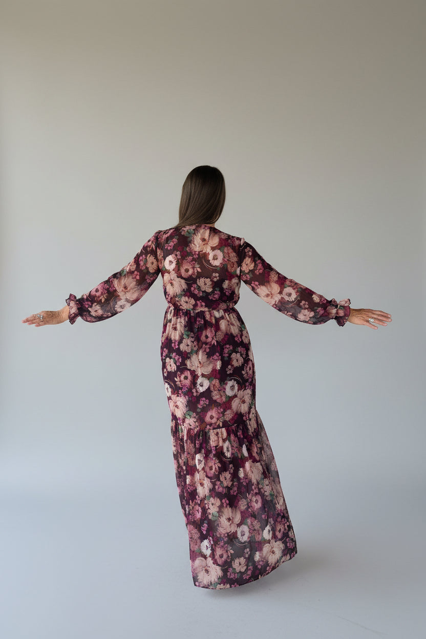 Woman in burgundy floral maxi dress looking down, showcasing tiered hem and floral chiffon fabric, outdoor pavilion
Back view 