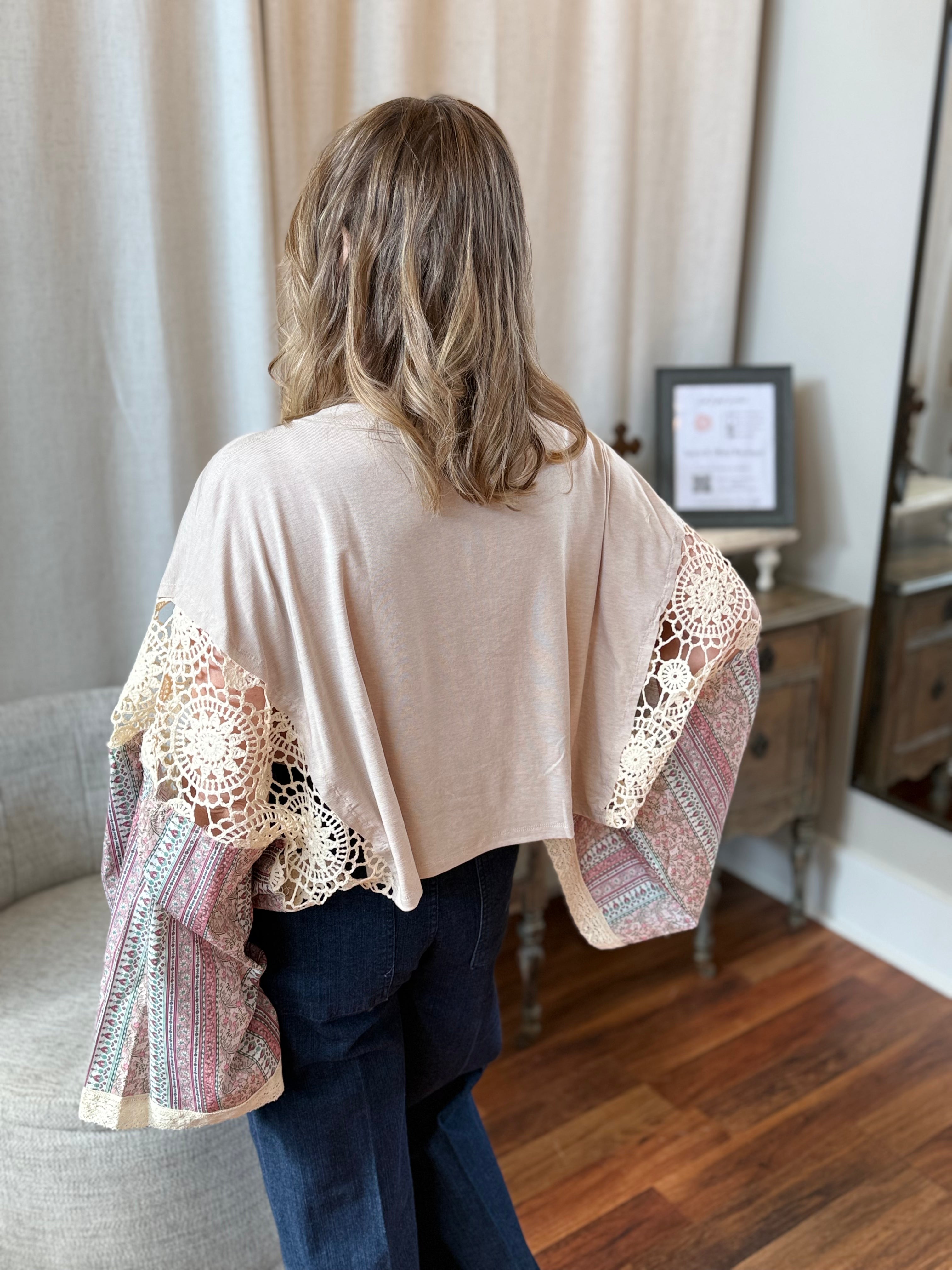 Woman wearing a beige kimono-style garment with lace details in a room.