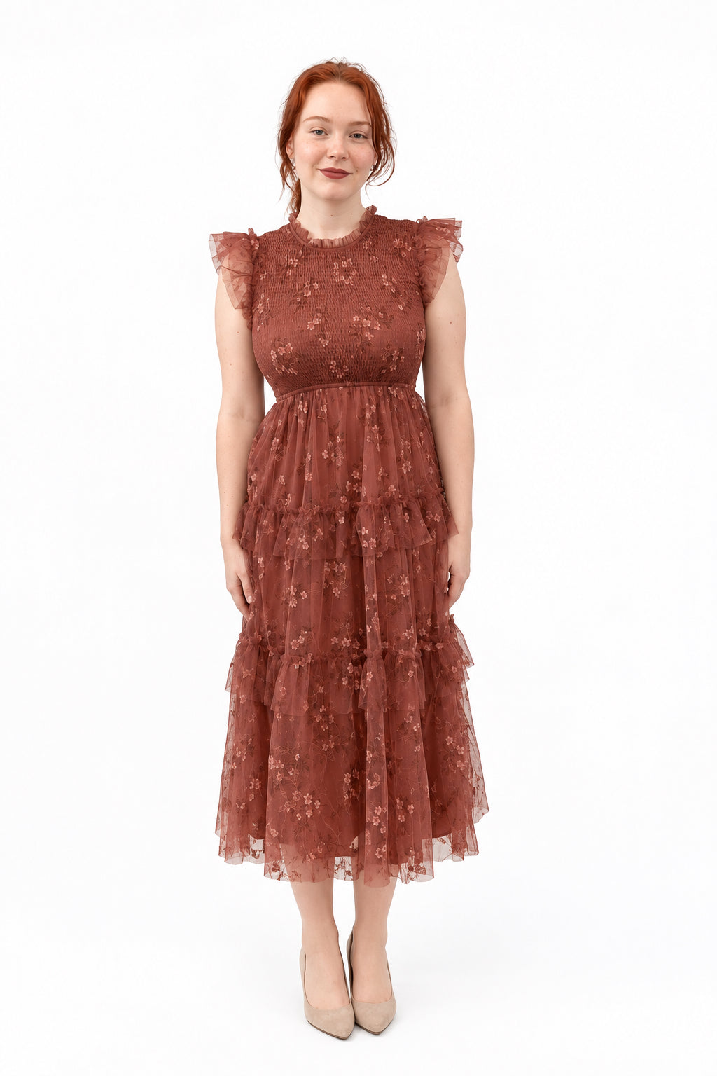 A woman wearing a dusty rose terracotta tiered lace midi dress with ruffled cap sleeves.