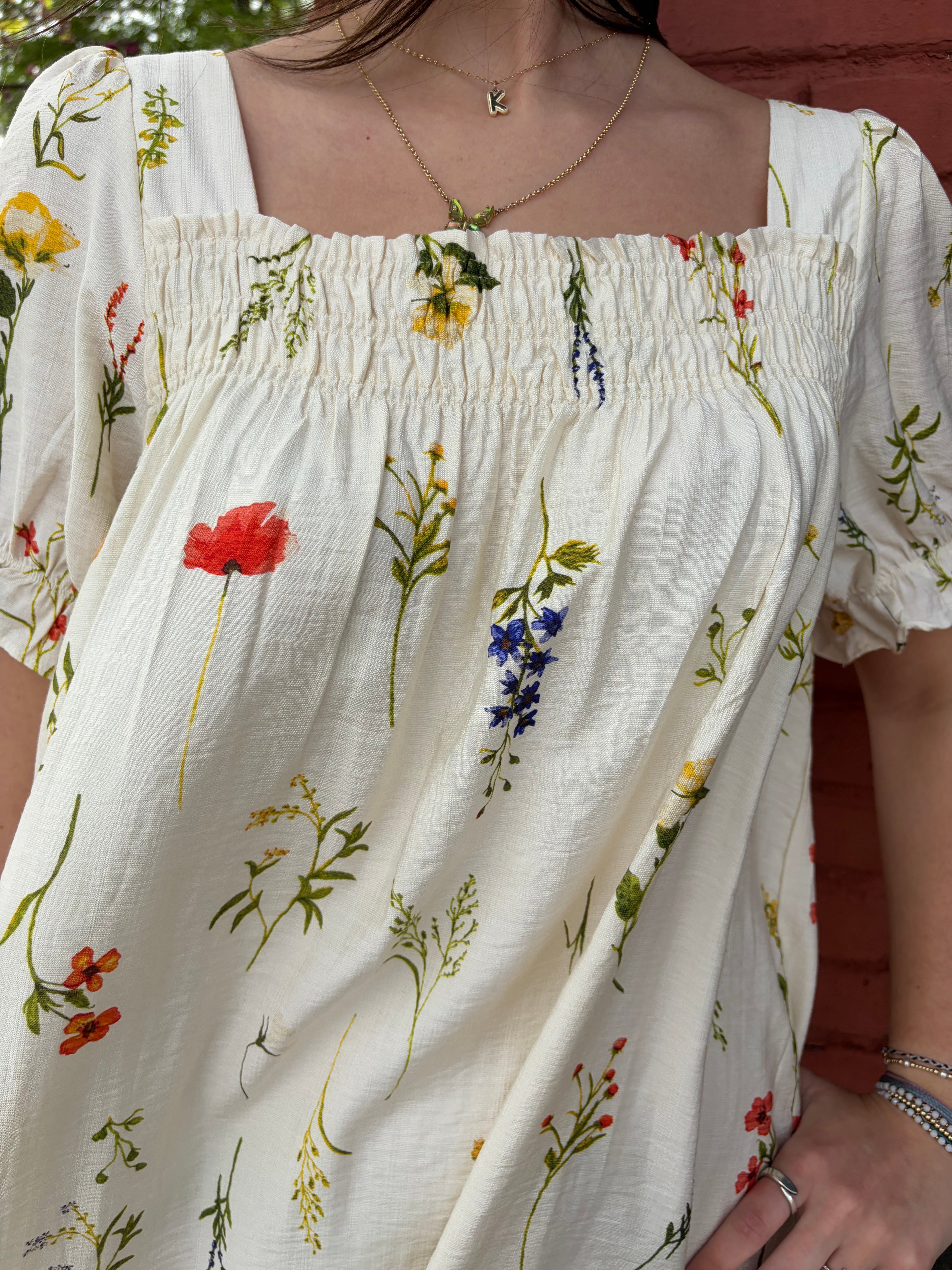 Close-up of a breezy days creamy white and floral pattern dress worn by model.