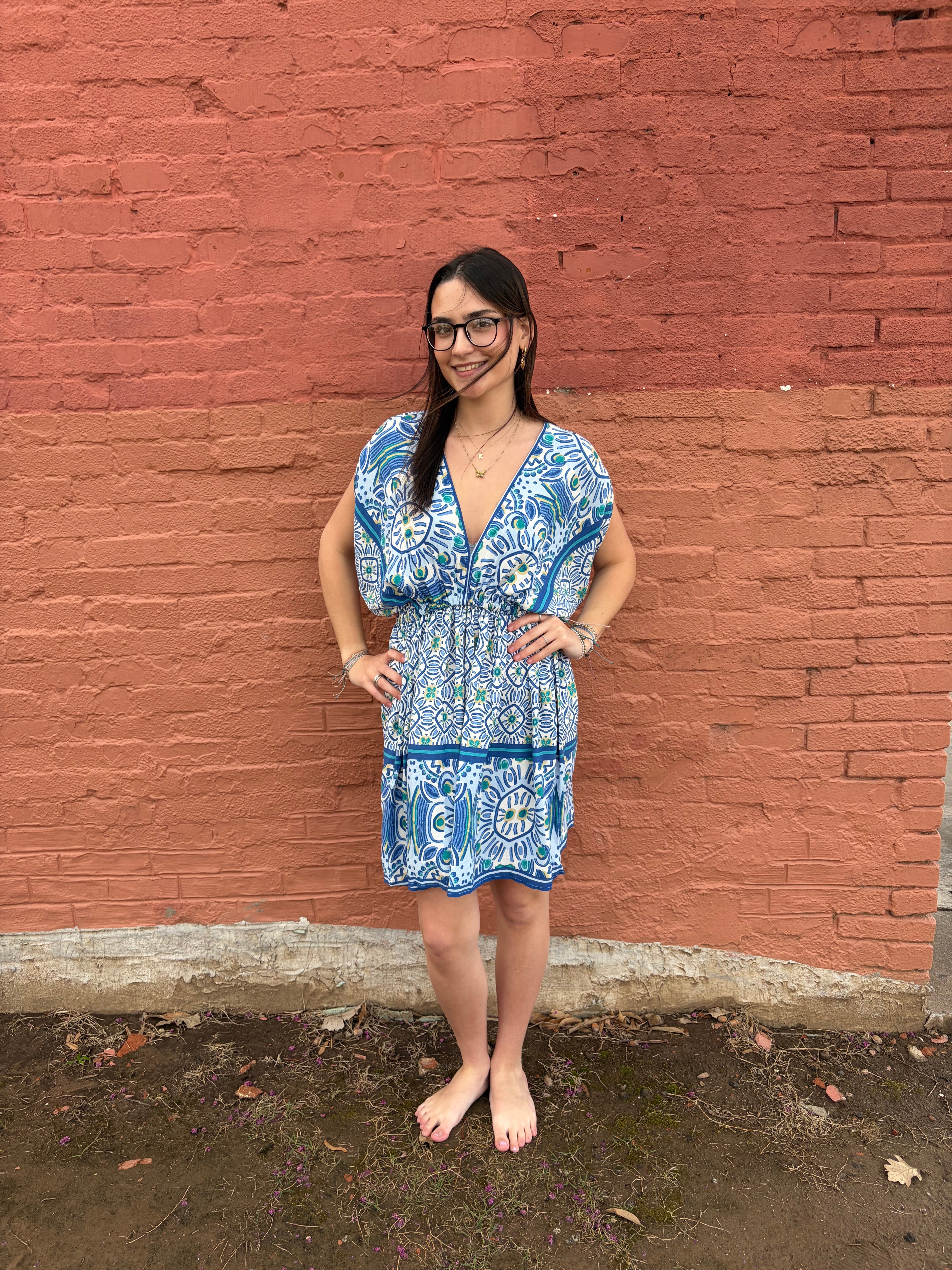 Woman in a blue dress standing on a red brick surface