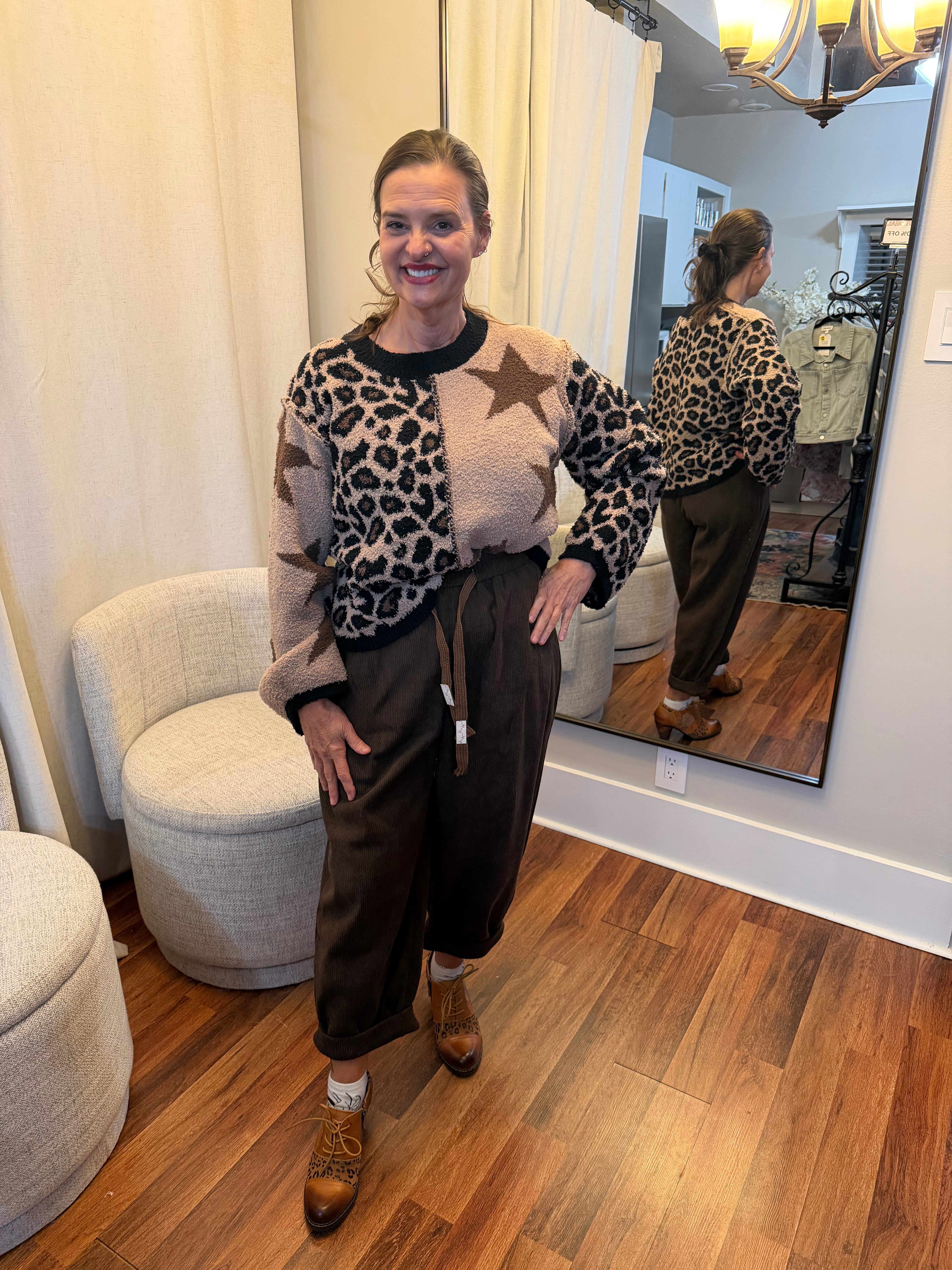 Model wearing high-waisted brown corduroy daddy pants with relaxed fit, drawstring waist, and rolled cuffs styled with a star and leopard patch sweater.