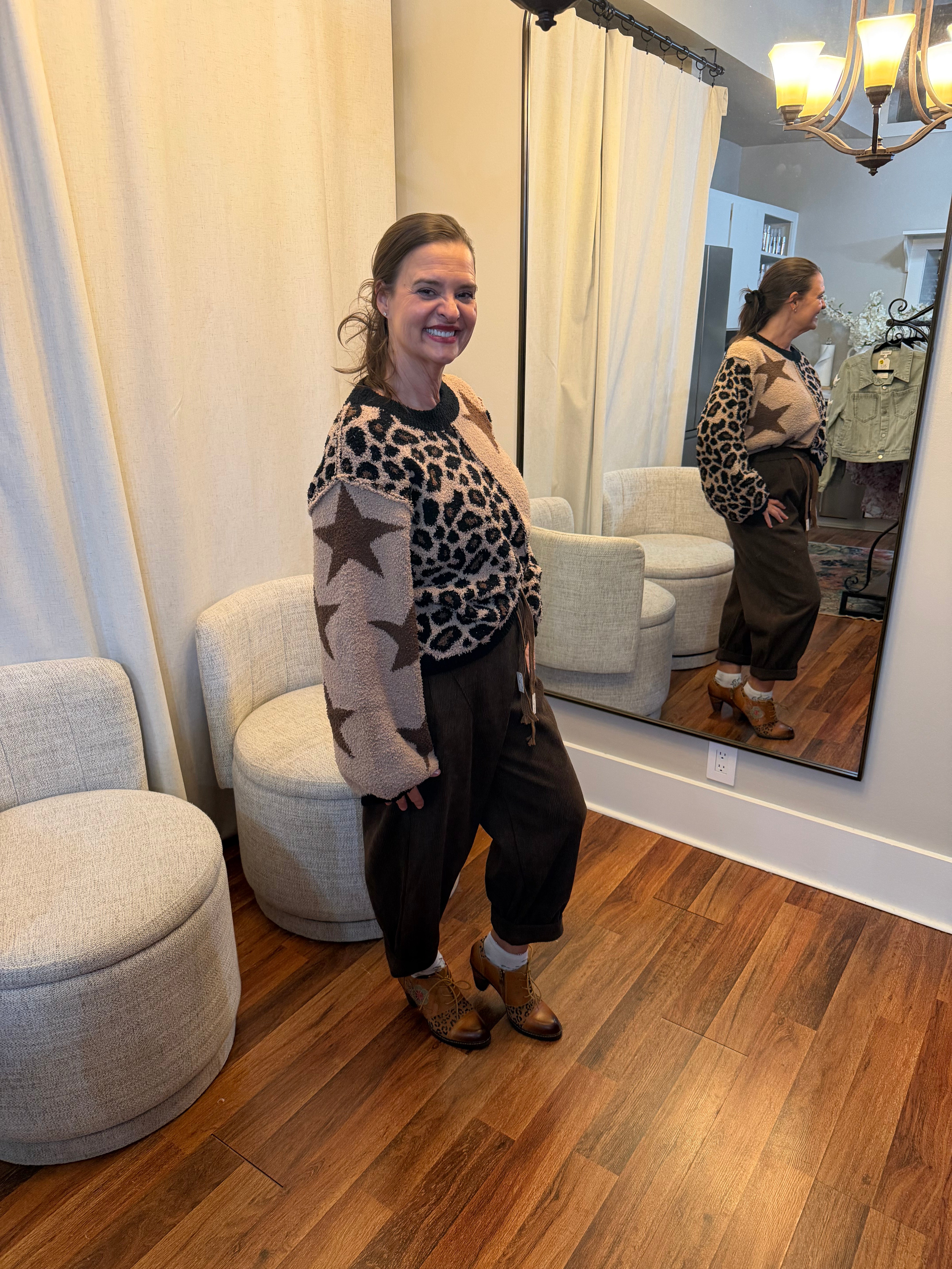 Side view of Model wearing high-waisted brown corduroy daddy pants with relaxed fit, drawstring waist, and rolled cuffs styled with a star and leopard patch sweater.”