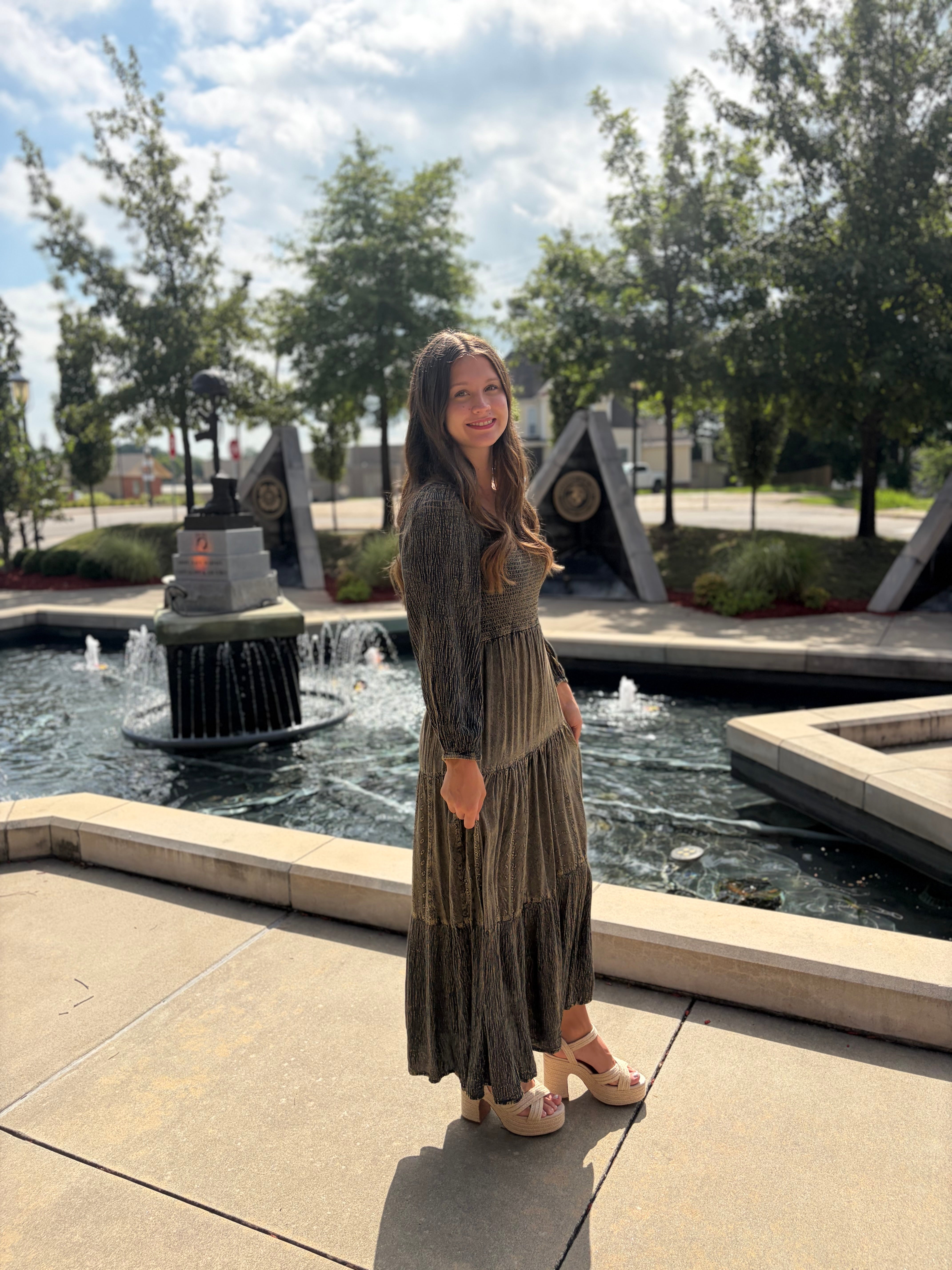 Amber tiered maxi dress with smocked bodice and long sleeves styled by a fountain