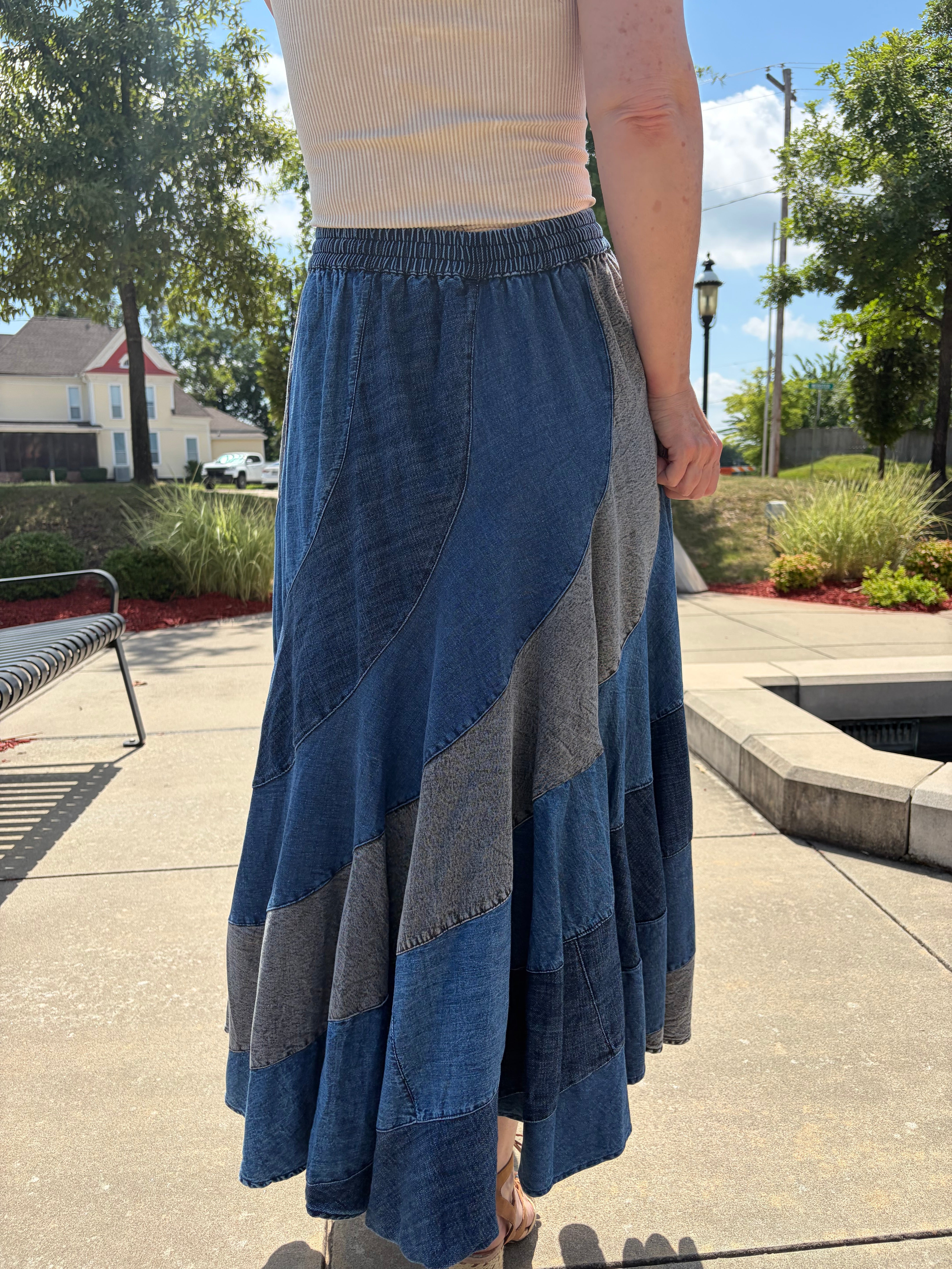 Back view close-up showing the swirling asymmetrical patchwork denim panels and elasticated waistband