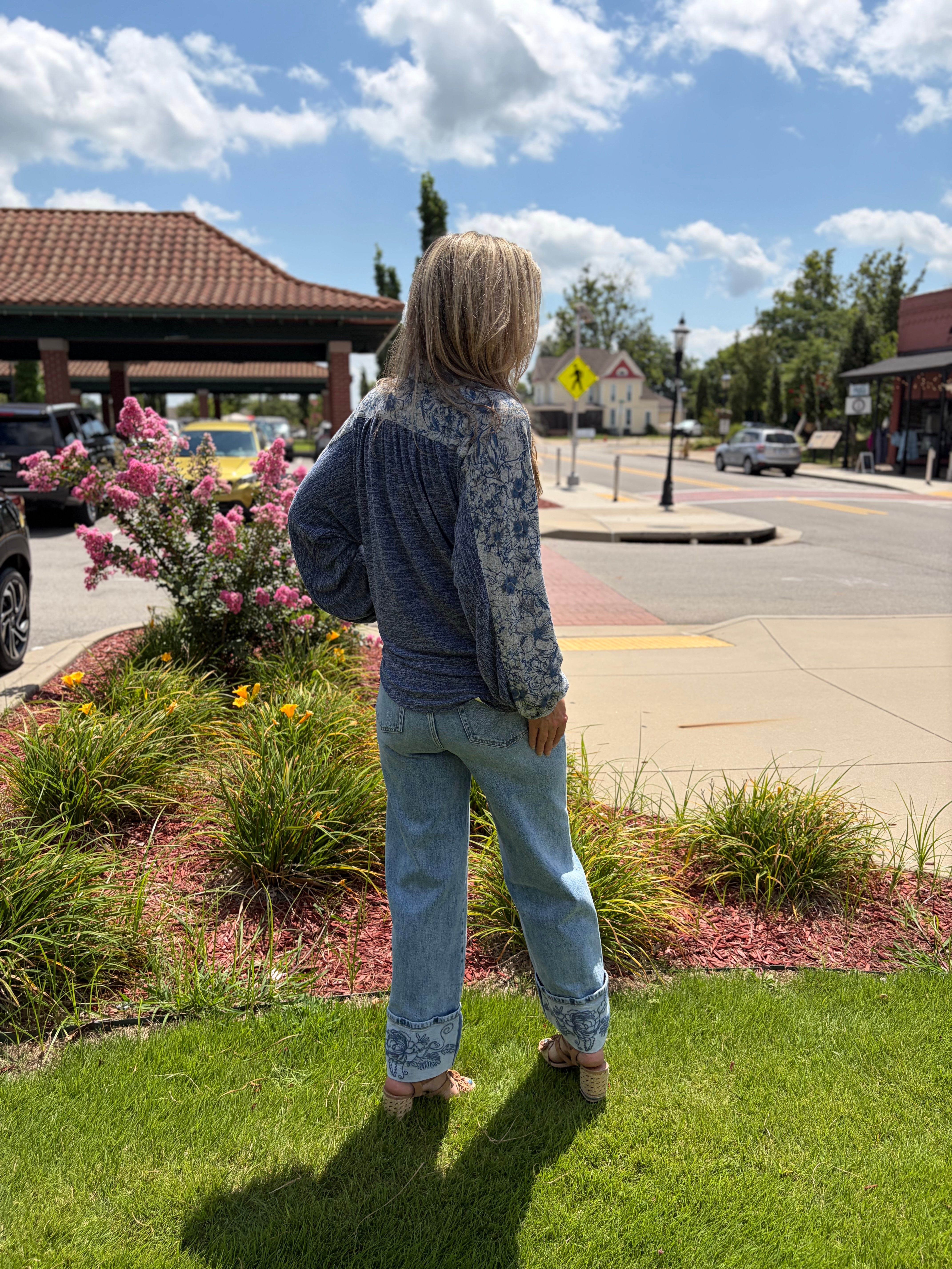 Back view of bohemian breeze sweater knit shirt in blue with floral embroidered balloon sleeves and relaxed fit, styled with wide-leg jean
