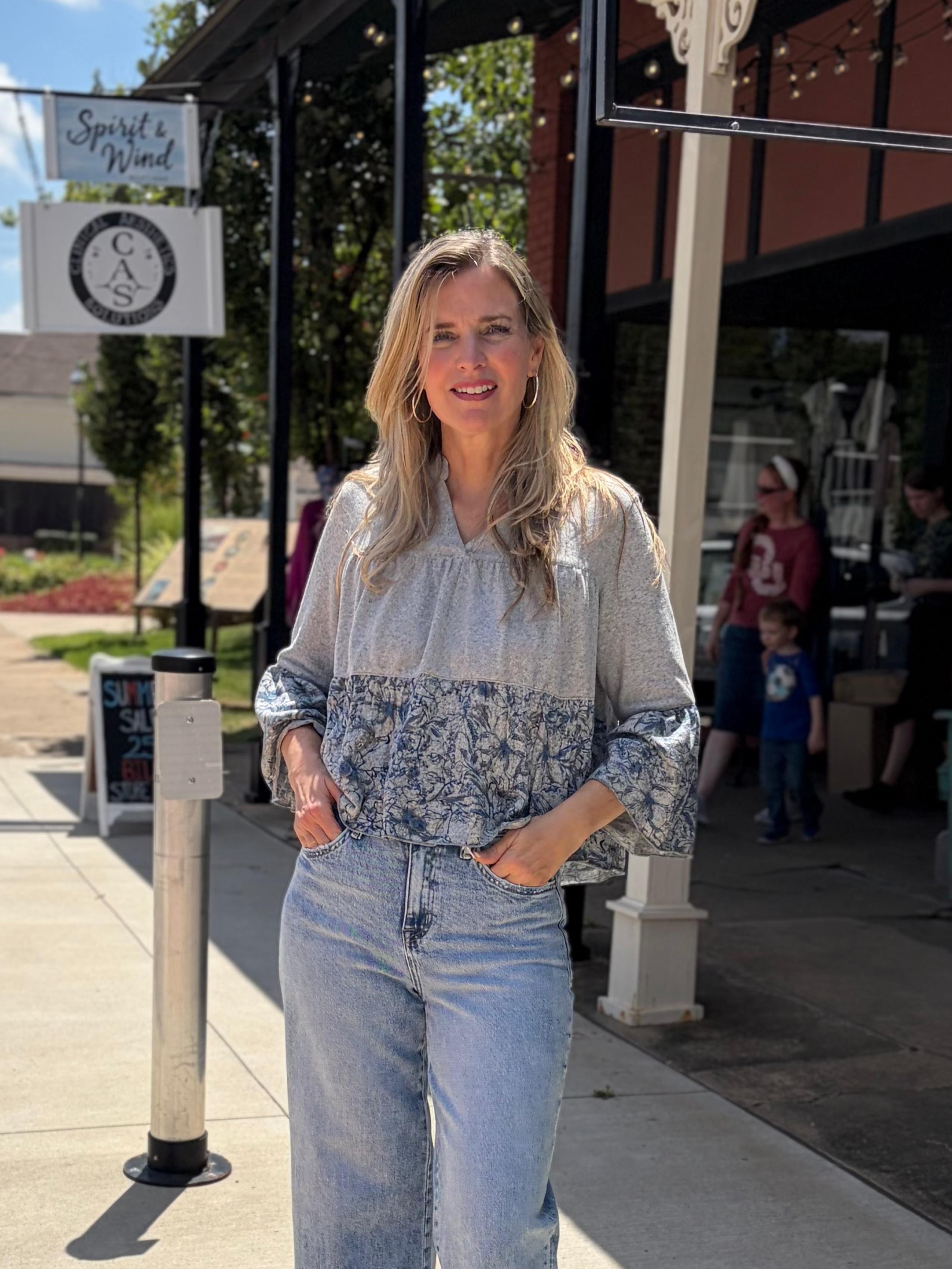 Outdoor full-body front, smiling on downtown sidewalk, wide-leg jeans + strappy sandals