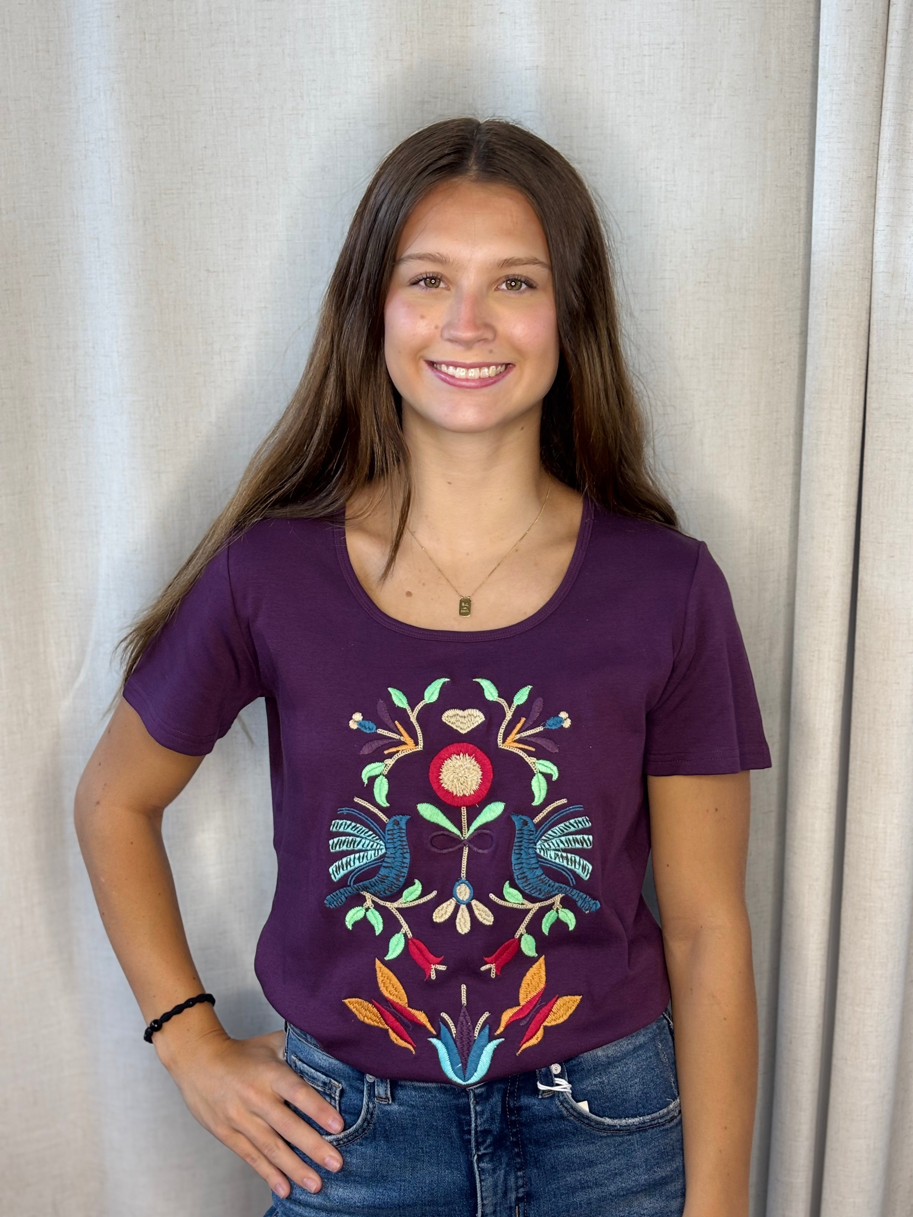 Anü Birds & Butterflies Embroidered Tee in plum — front view with colorful folk-art bird, butterfly, and floral embroidery on 100% cotton tee