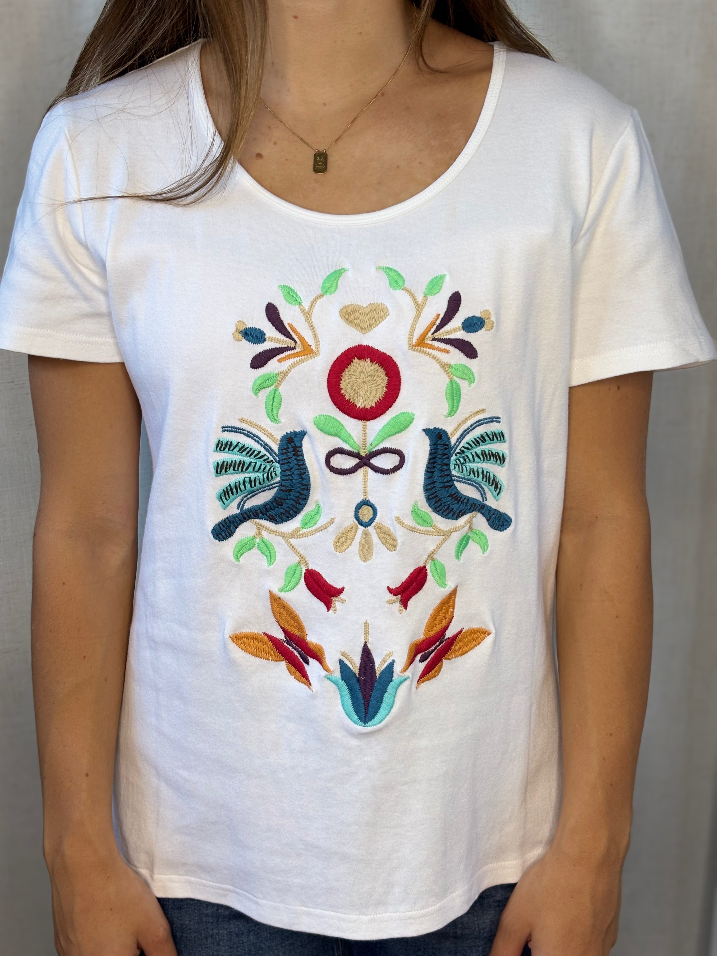 Close-up of hand embroidery detail on Anü Birds & Butterflies Tee — folk-art birds, florals, and botanical motifs in multicolor thread on white cotton