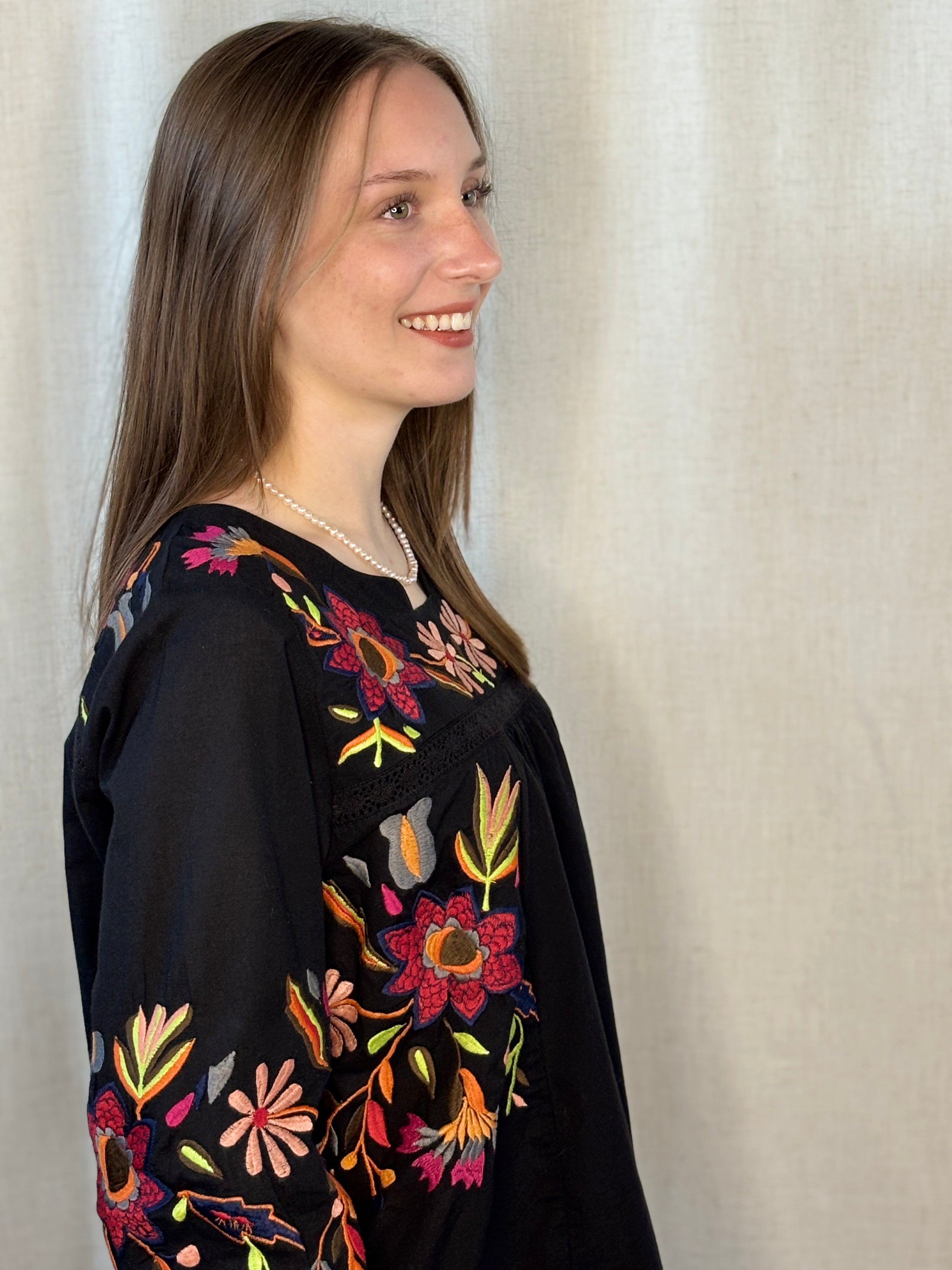Anü Vibrant Floral Embroidered Blouse in black — side profile showing flowy fit and vibrant floral embroidery along sleeves and body