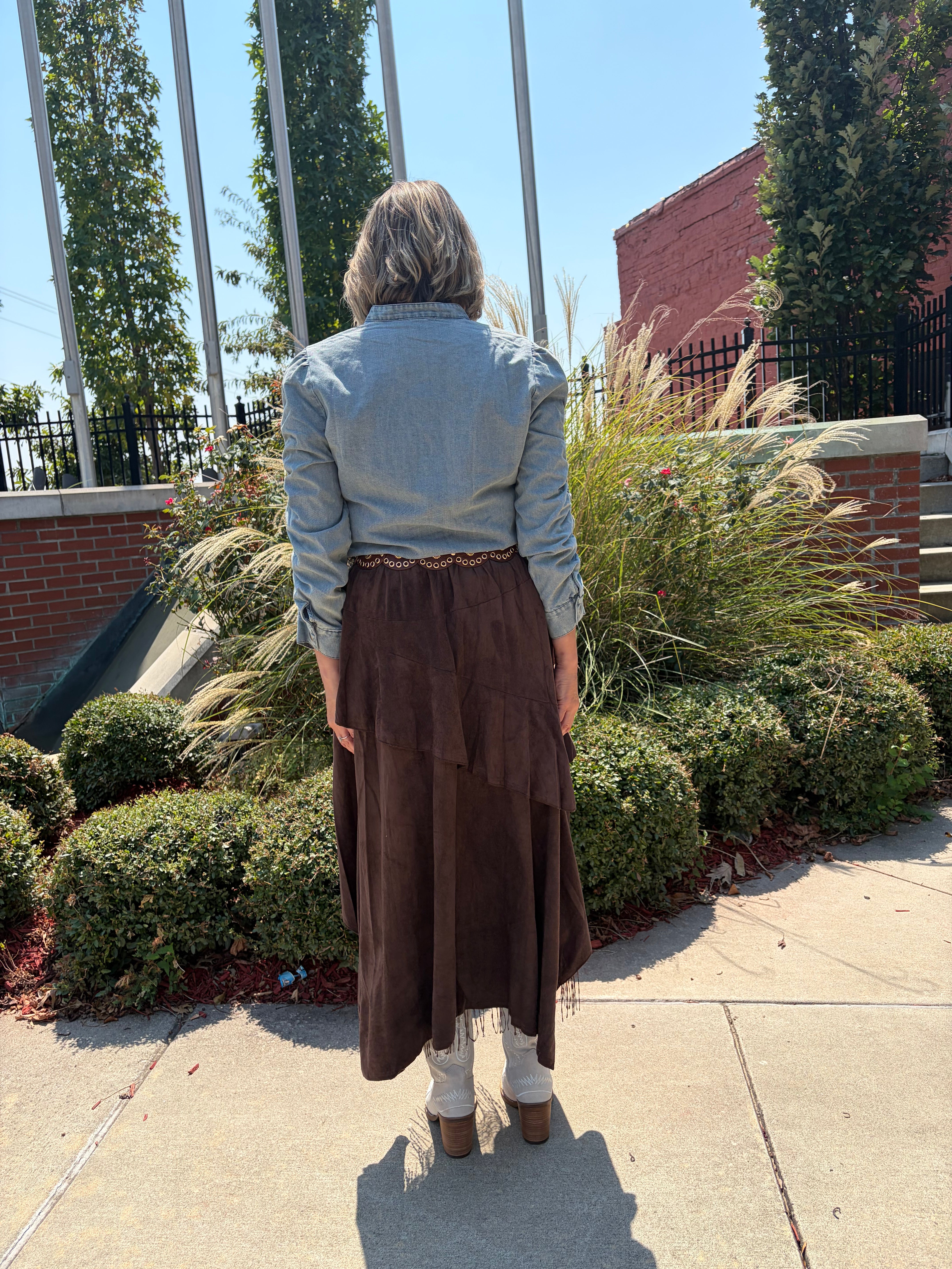 Boho Layered Lace Skirt in dark chocolate brown showing asymmetrical tiered back hem and grommet waistband detail, styled with light blue denim top, back view outdoors