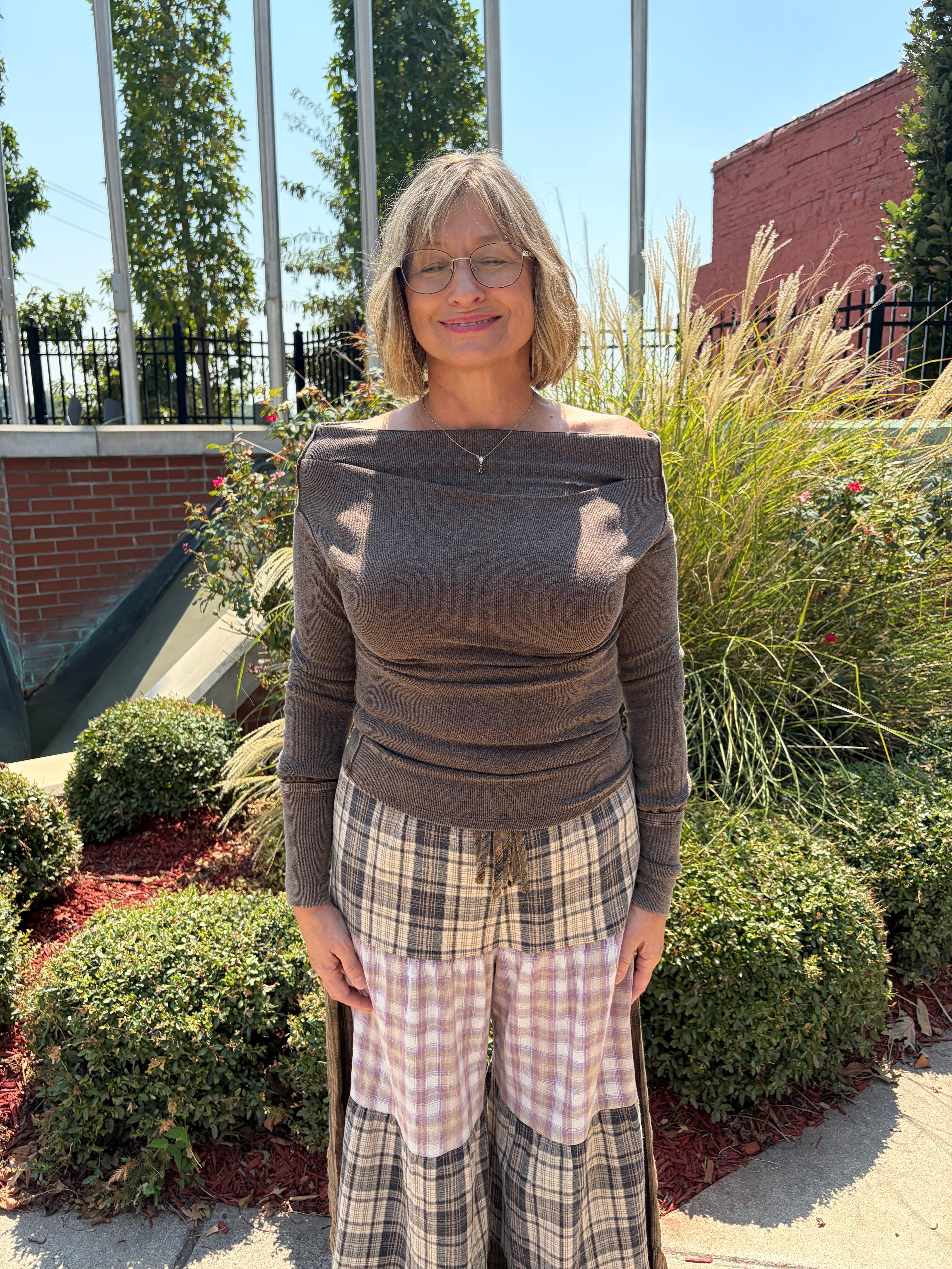 Patchwork Plaid Maxi Pants in tiered brown and blush plaid panels, front full-length view outdoors, styled with brown off-shoulder top