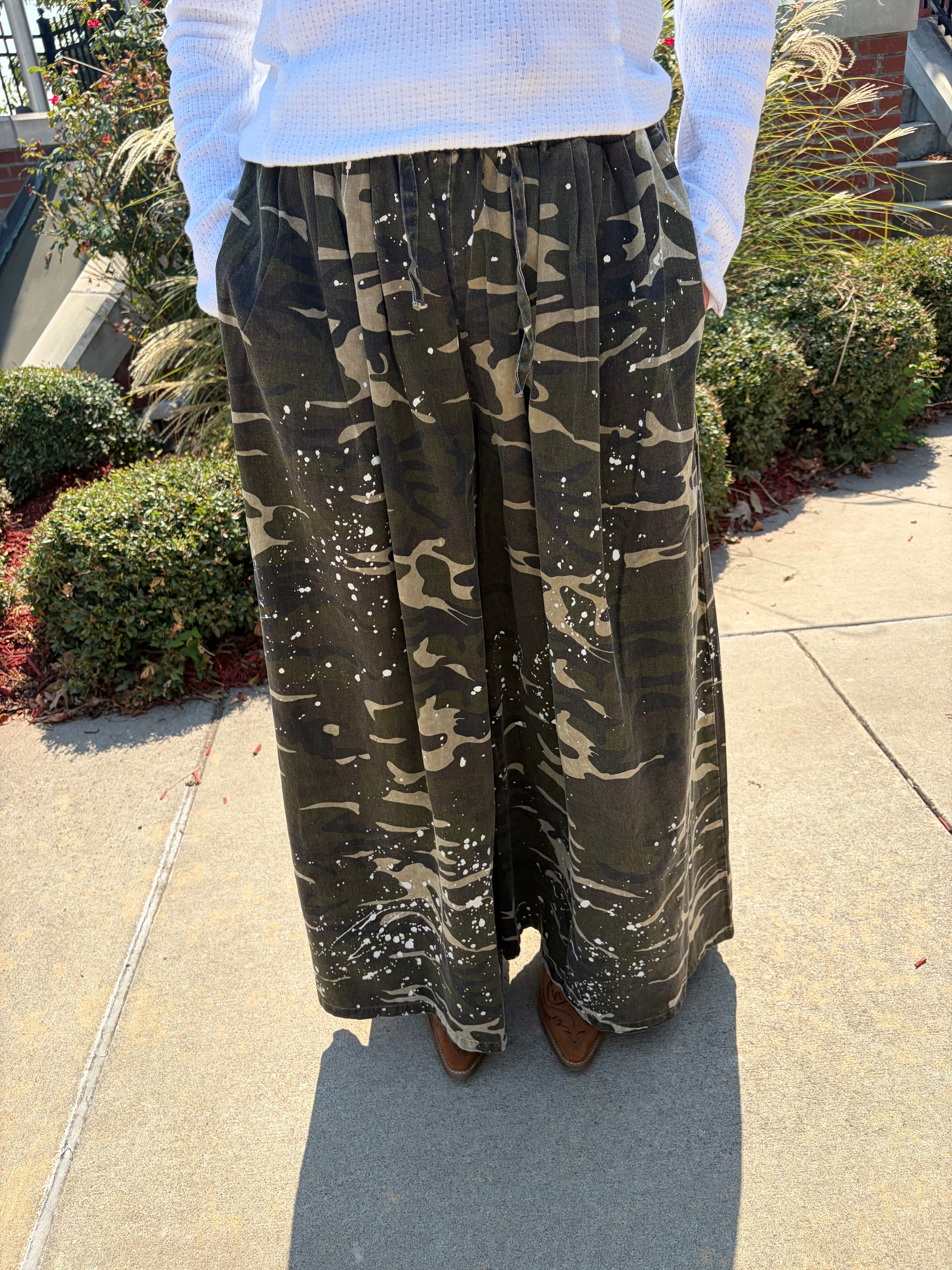 Close-up front view of Blue Velvet paint splash camo wide leg pants showing elastic drawstring waistband and white paint splash detail
