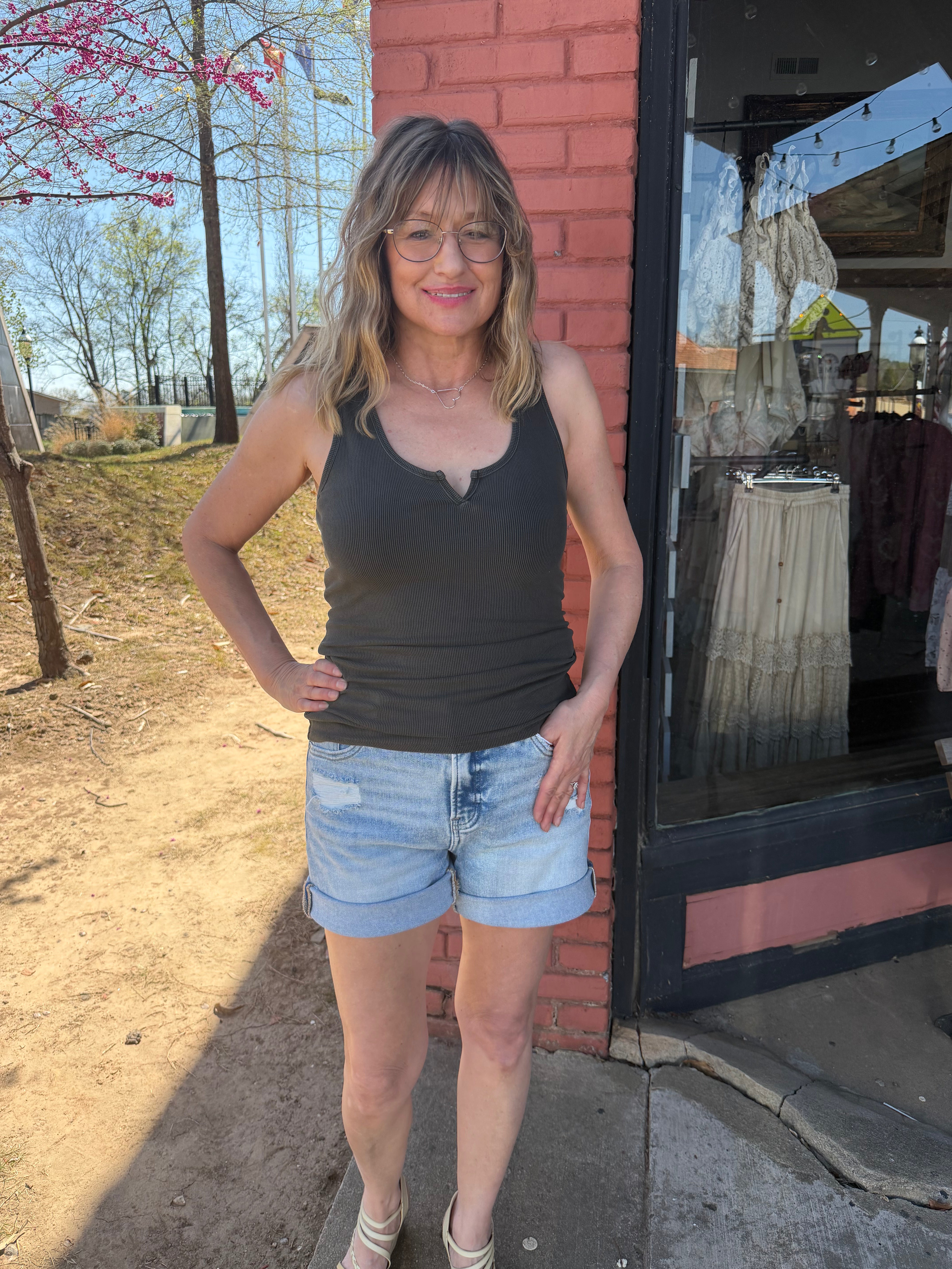 Woman standing outside a store with a brick wall and outdoor setting.