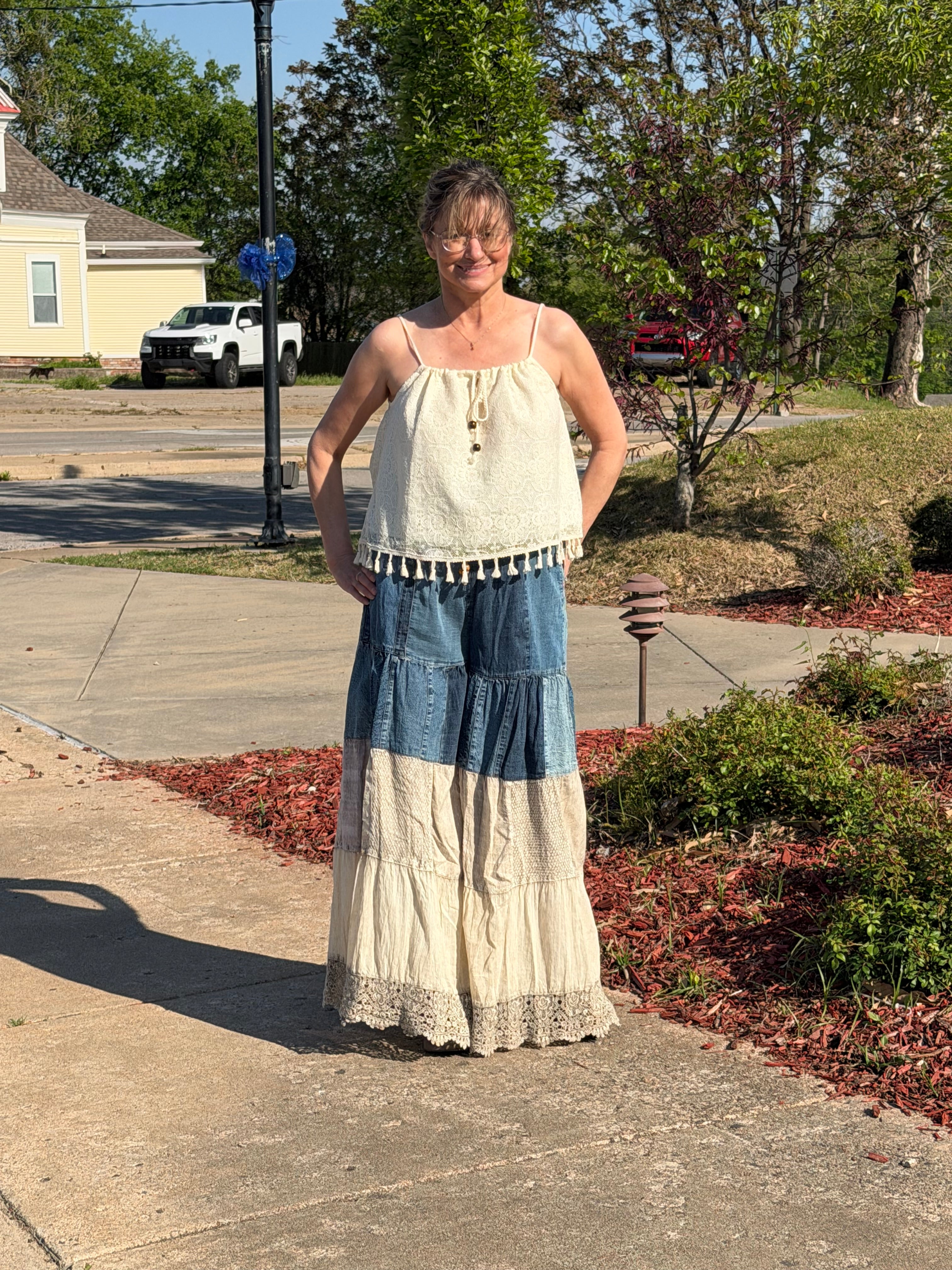 Person wearing a dress with denim accents standing on a sidewalk.