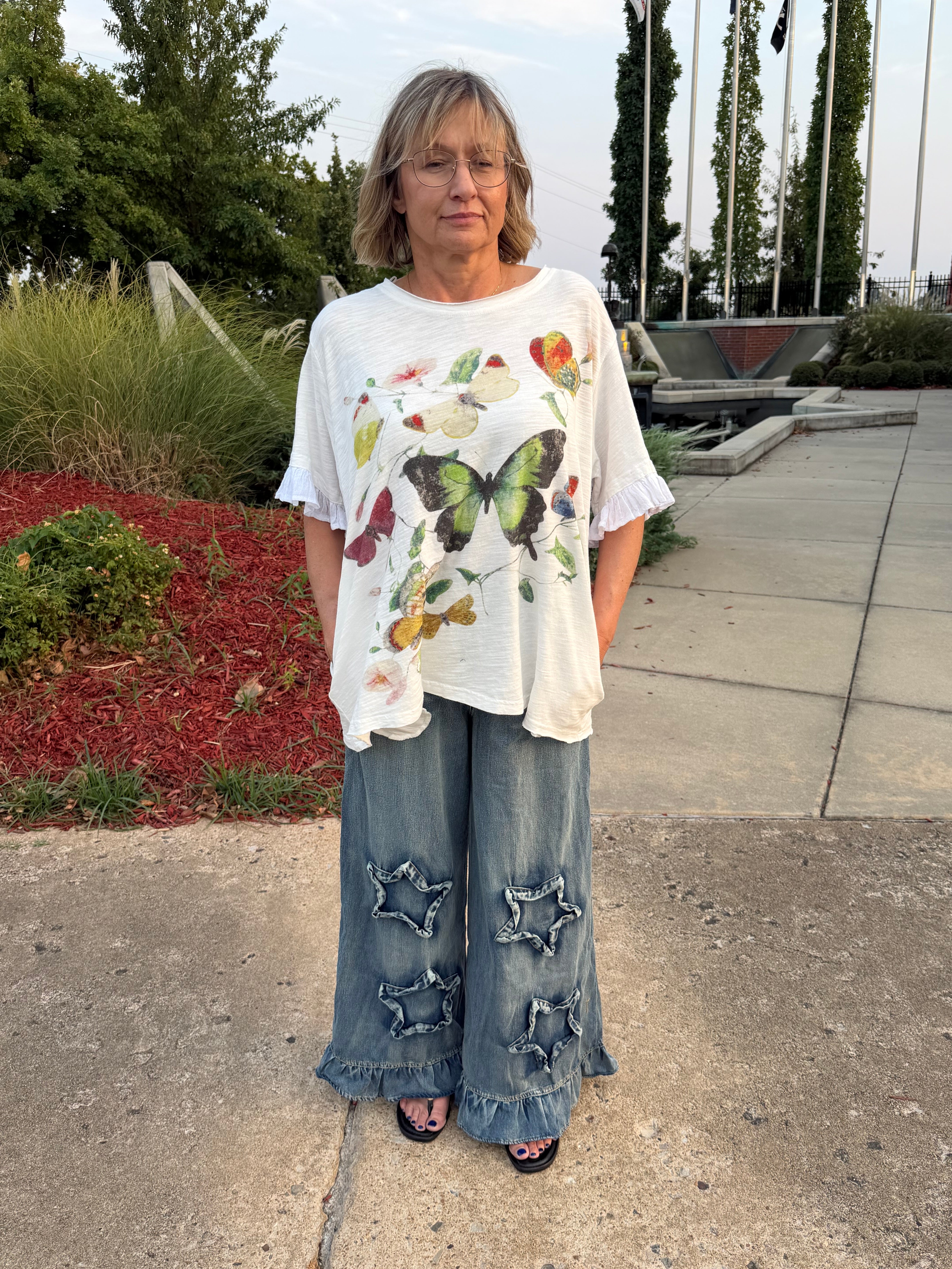 Front view of woman wearing Blue Velvet ruffled star patch wide leg denim pants with butterfly graphic tee, full length