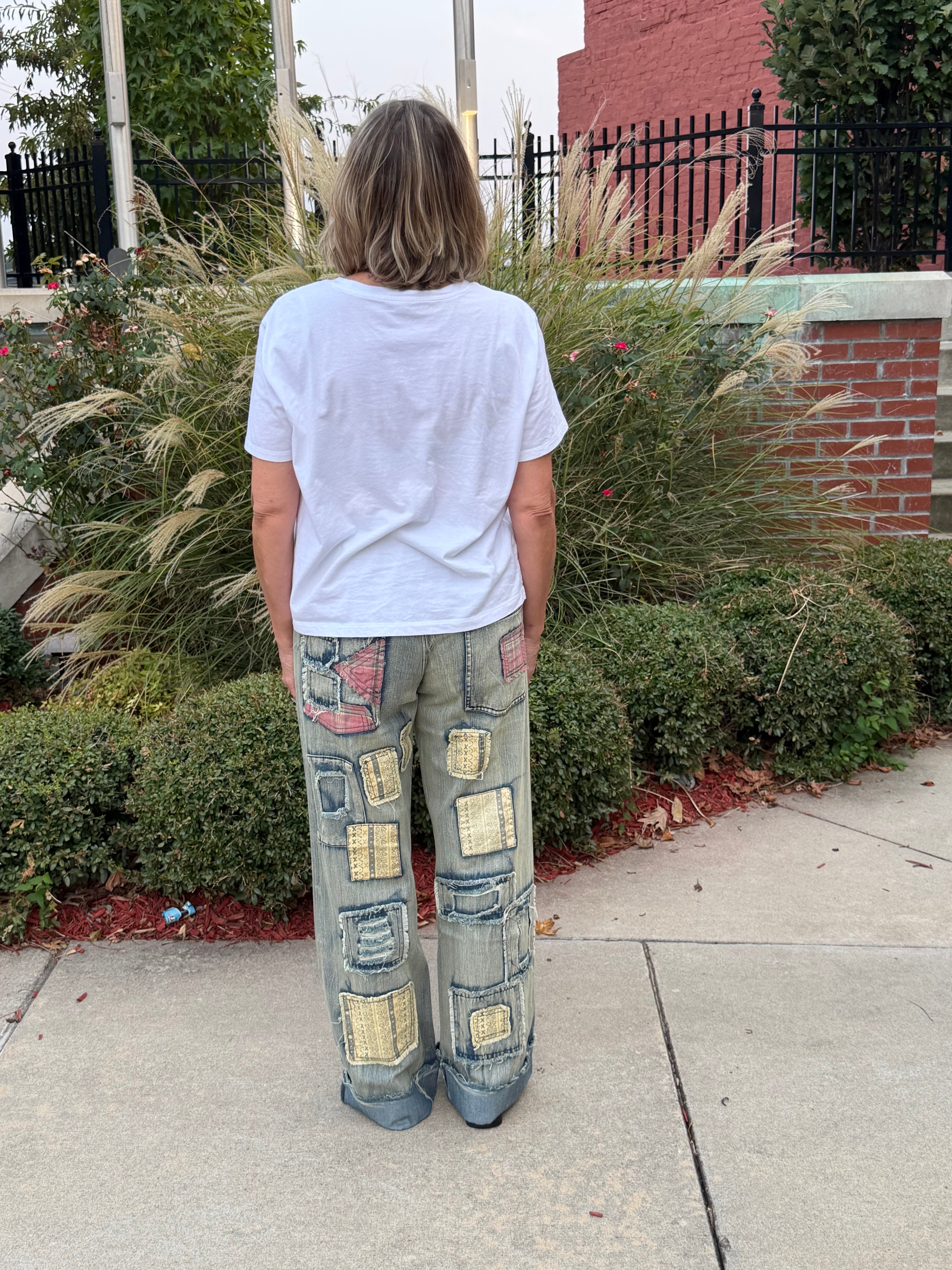 Back view of woman in BlueVelvet artisan patchwork denim jeans and showing cuffed hem and layered patch detail
