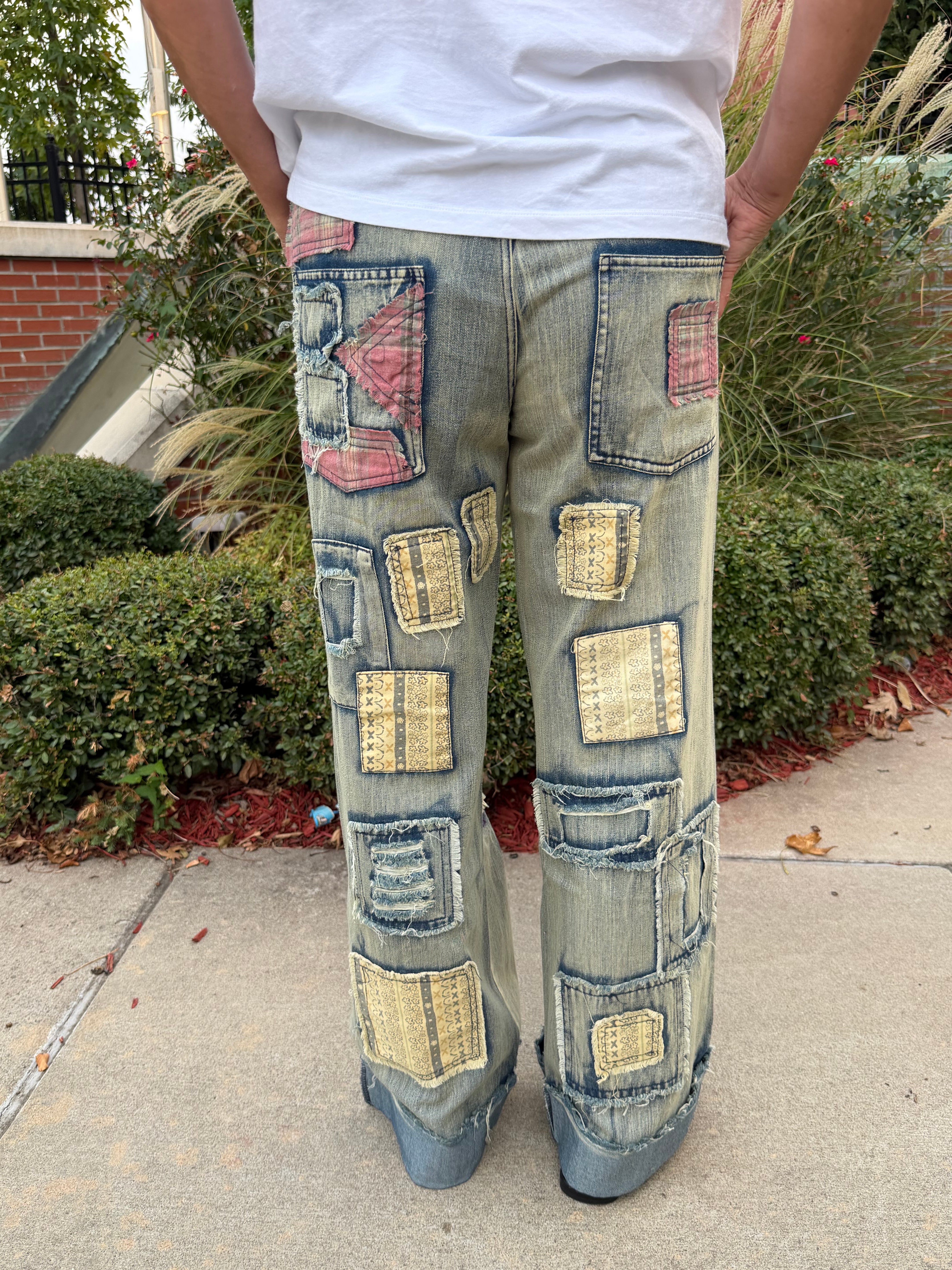 Back view of woman wearing Blue Velvet artisan patchwork embroidered wide leg denim jeans showing full-coverage patch detail and cuffed hem