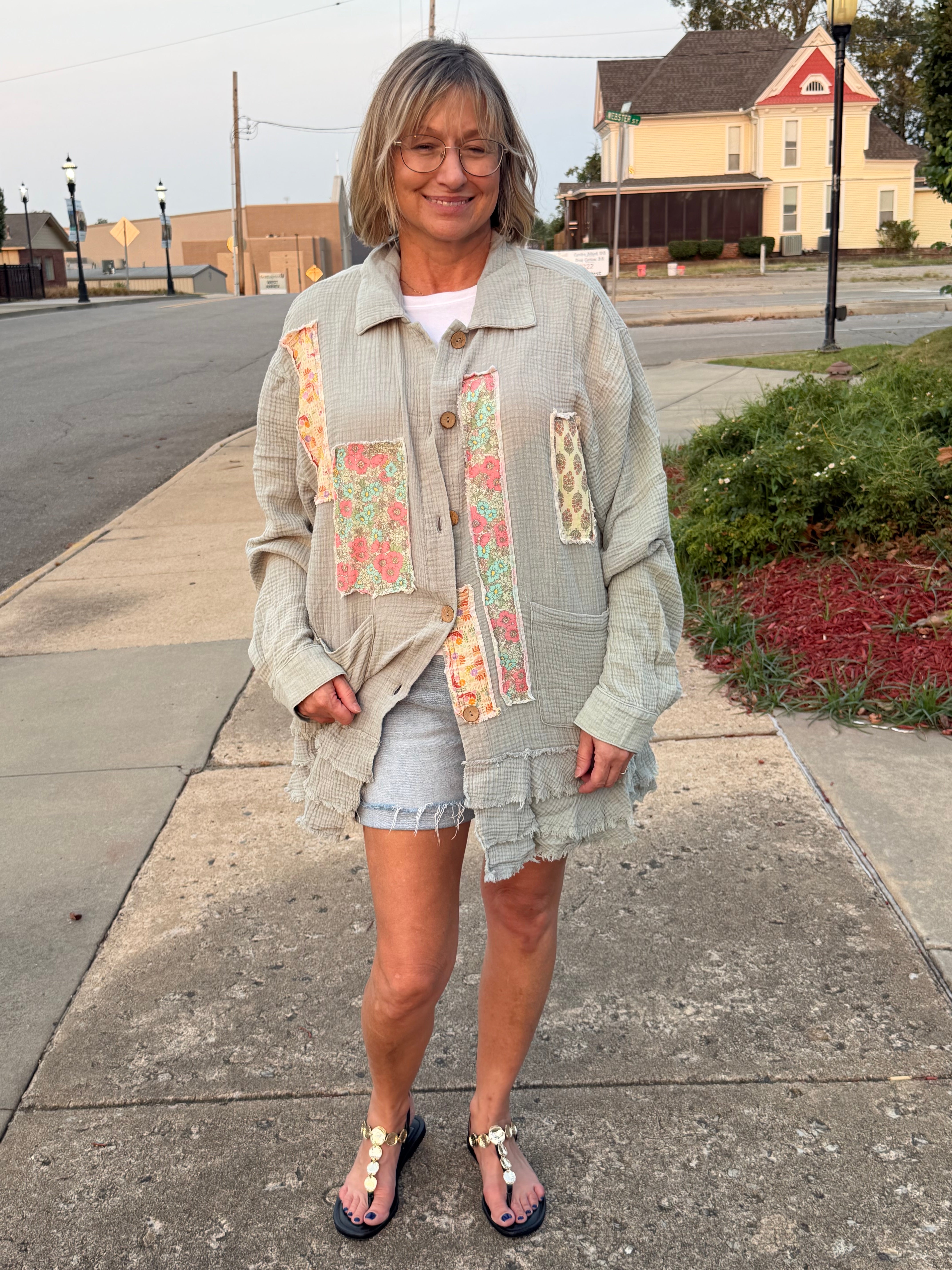Woman smiling wearing Blue Velvet sage patchwork ruffle hem gauze shirt open over white tee, front view, full length outdoor shot
