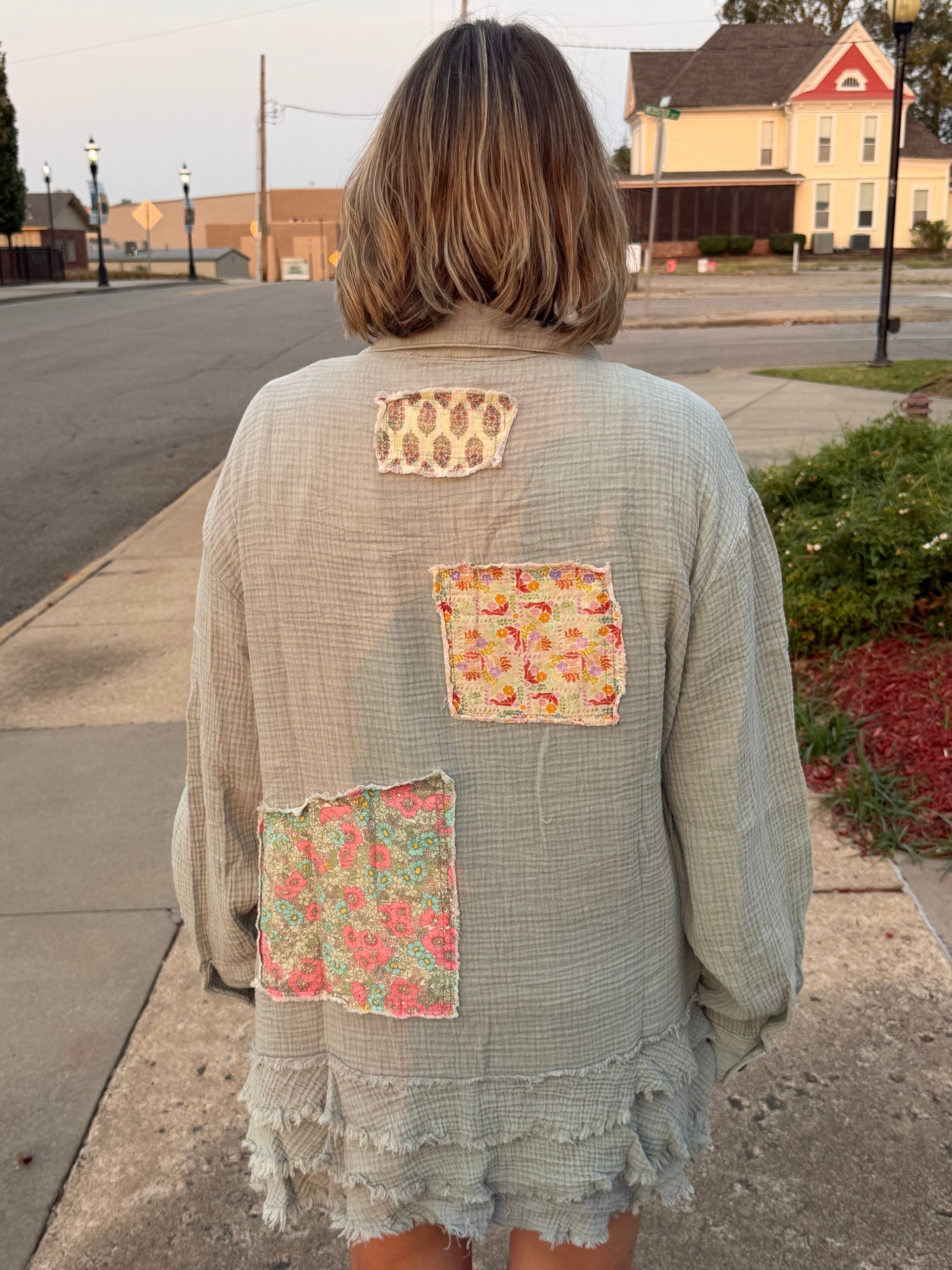 Back view of woman wearing Blue Velvet sage gauze patchwork shirt showing three floral fabric patches and layered frayed ruffle hem
