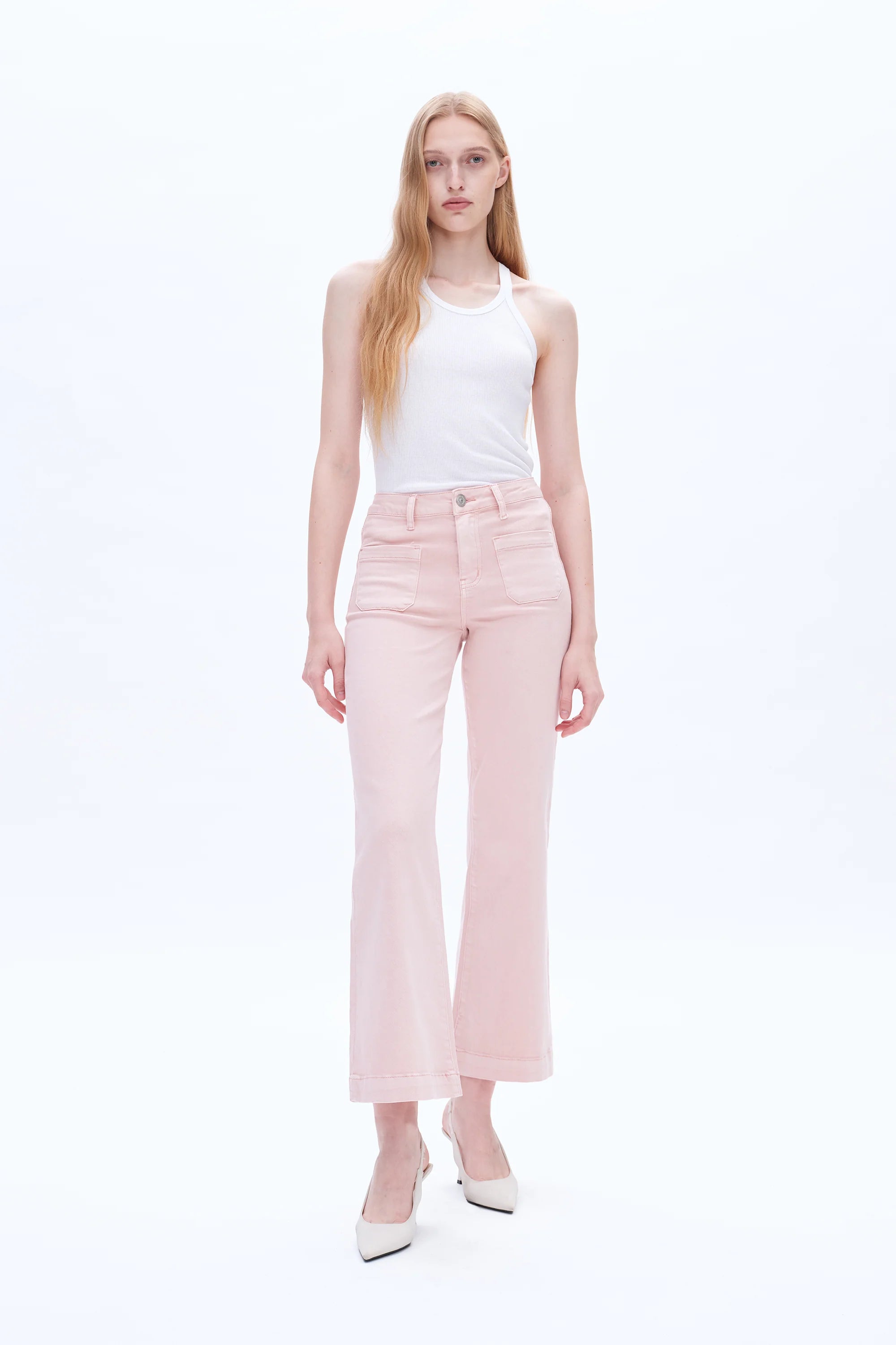 Woman wearing a white sleeveless top and light pink pants on a white background