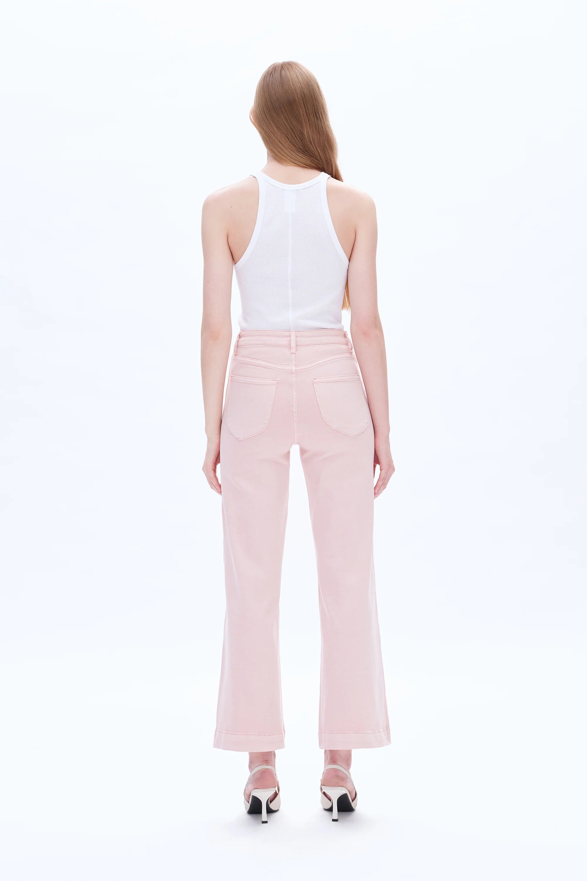Woman wearing a white sleeveless top and pink pants on a white background