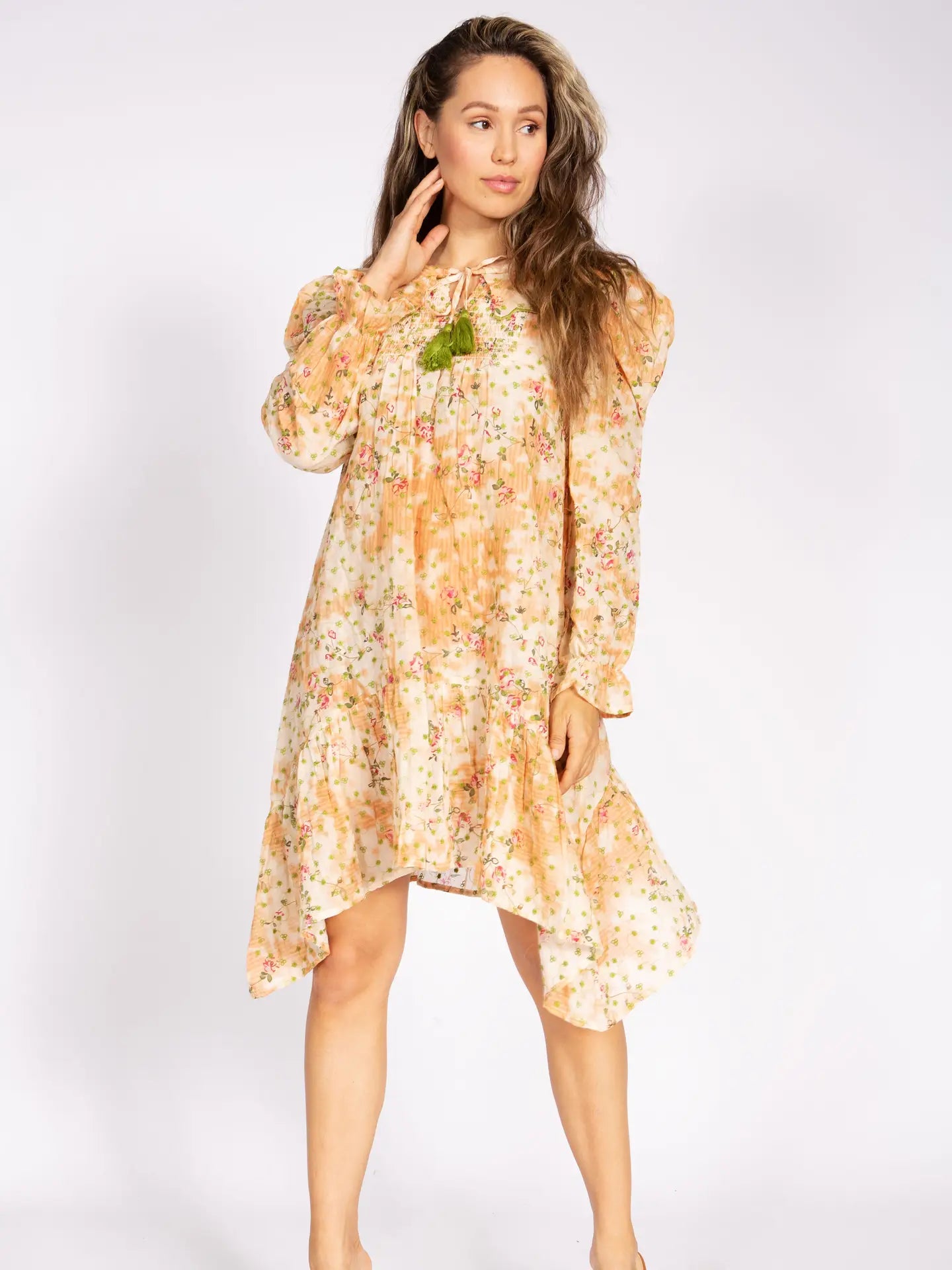 Apricot Blossom Nu Vintage Dress – flowing apricot floral chiffon mini dress with long puff sleeves, ruffle hem, and green tassel tie neckline, styled on model – Spirit & Wind Boutique
