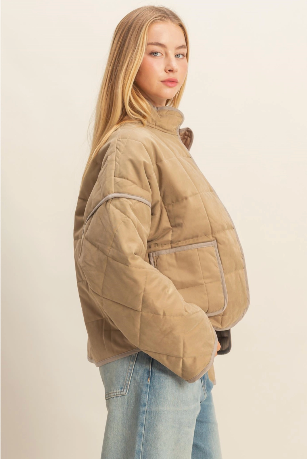 Woman wearing a beige quilted jacket on a plain background