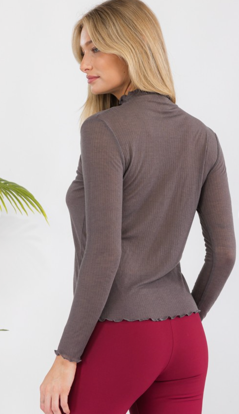 Woman wearing a brown long-sleeve top and red pants on a white background