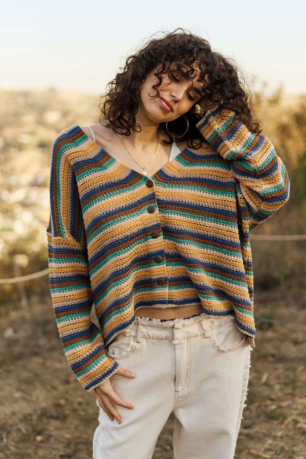 Model in a relaxed fit striped knit cardigan with button front, styled with cream denim pants for a boho casual look.