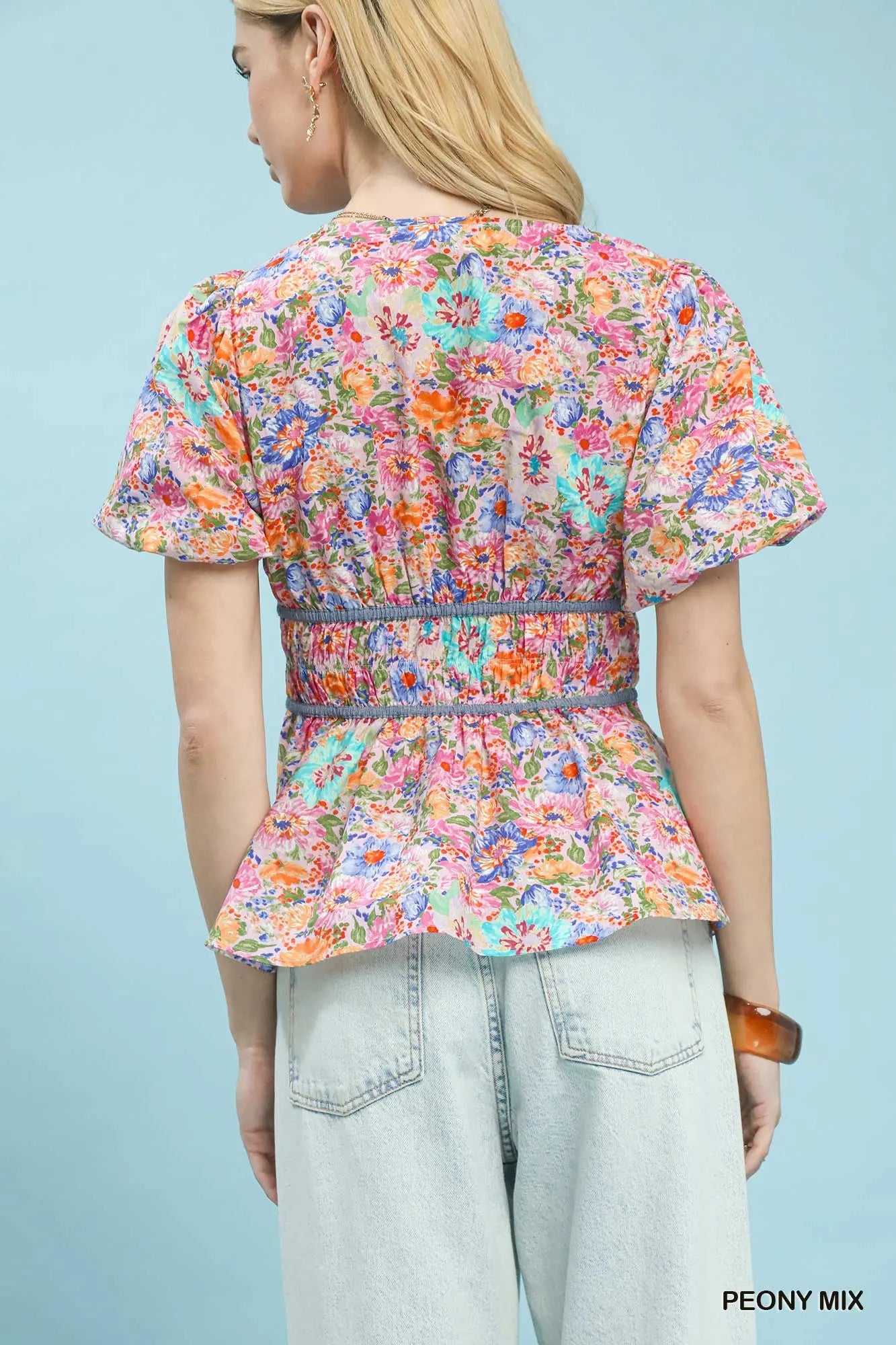 Person wearing a colorful floral blouse with a light blue background