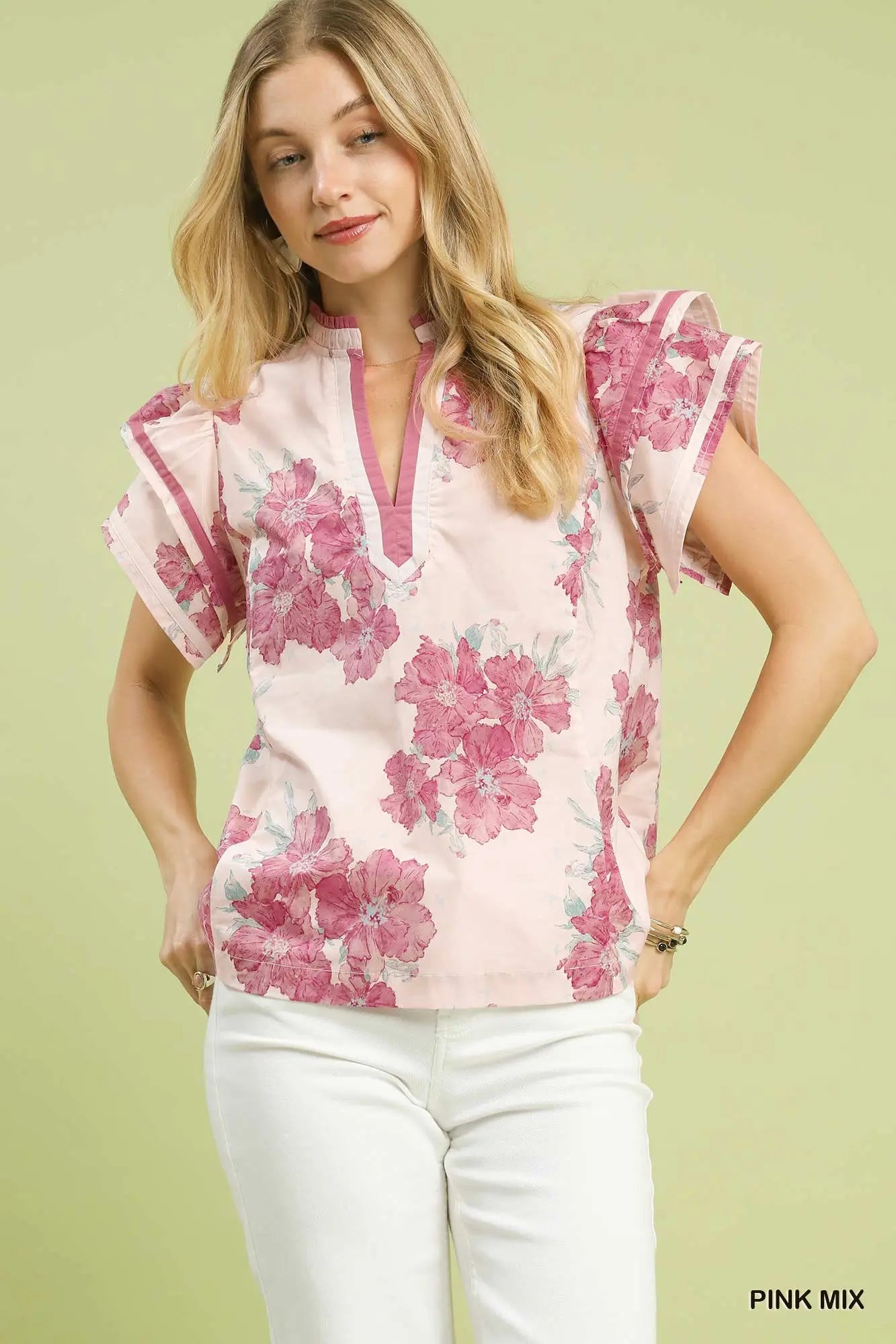 Woman wearing a floral pink and white top against a light green background