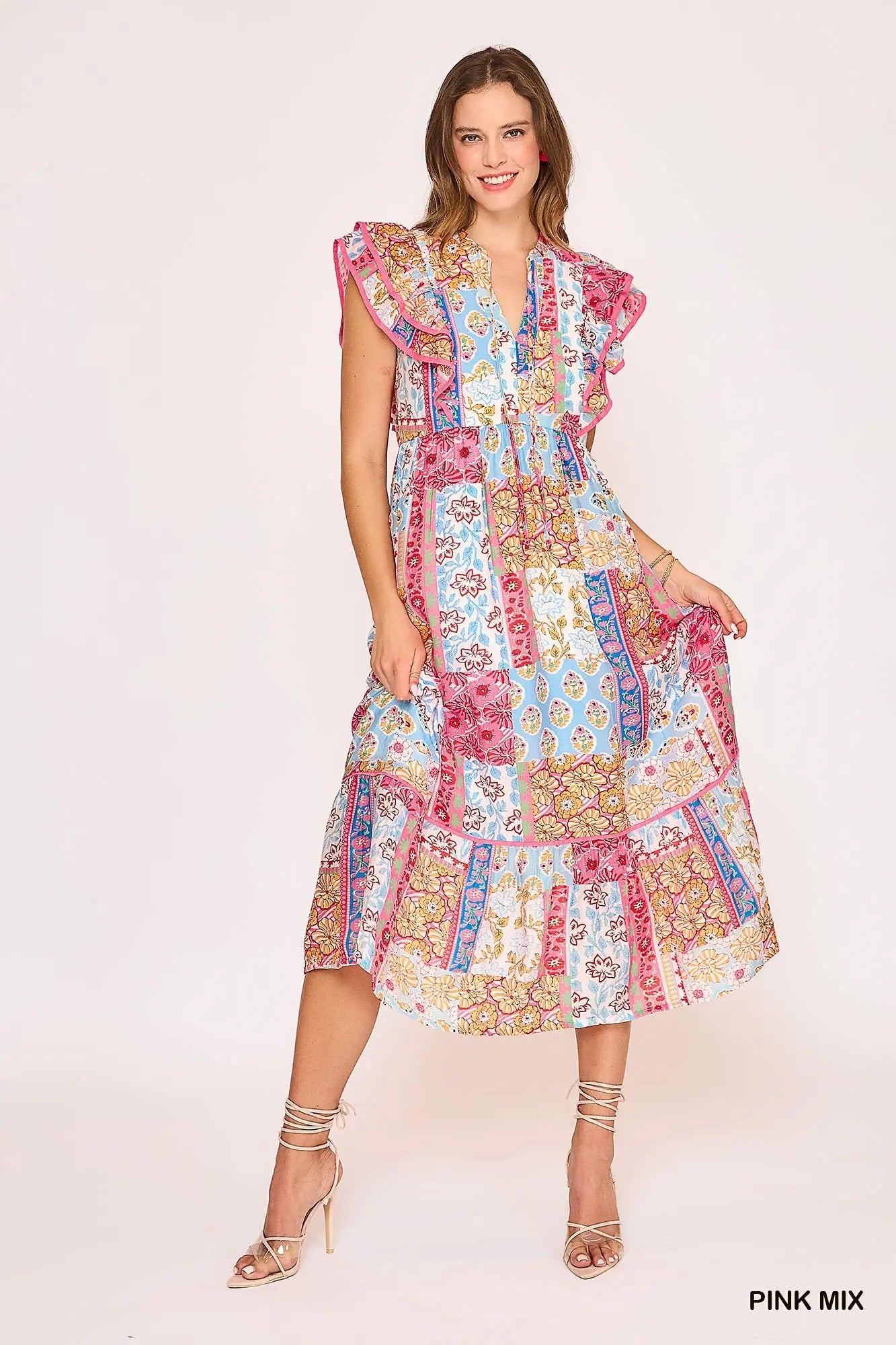 Woman wearing a colorful patchwork dress on a light pink background