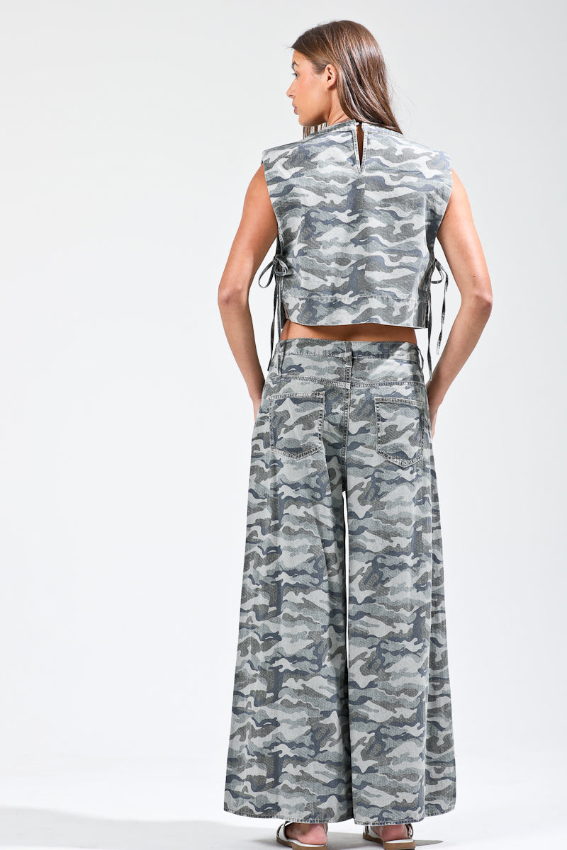 Woman wearing a camouflage sleeveless top and wide-leg pants on a white background