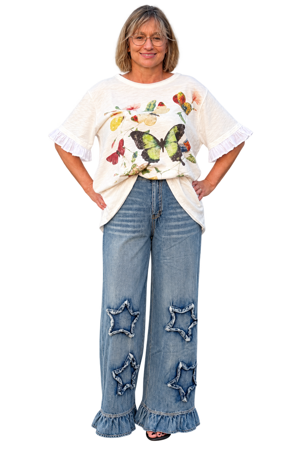 A woman modeling a cream-colored short-sleeve t-shirt with a colorful butterfly and floral print, paired with wide-leg blue jeans featuring star appliques and ruffled hems, against a plain white background.