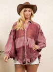 A woman wearing a dusty rose pink tie-dye button-up shirt with a frayed hem, paired with a brown cowboy hat and denim shorts.
