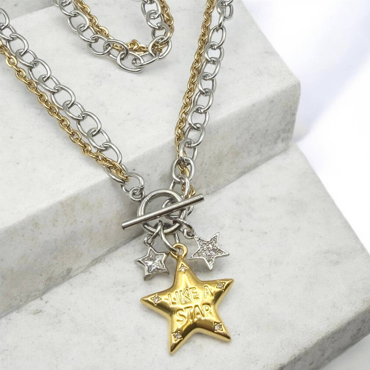 Necklace: Mixed-metal necklace with silver- and gold-tone chains, a toggle clasp, two small silver stars, and a gold star engraved “Like a Star.”

