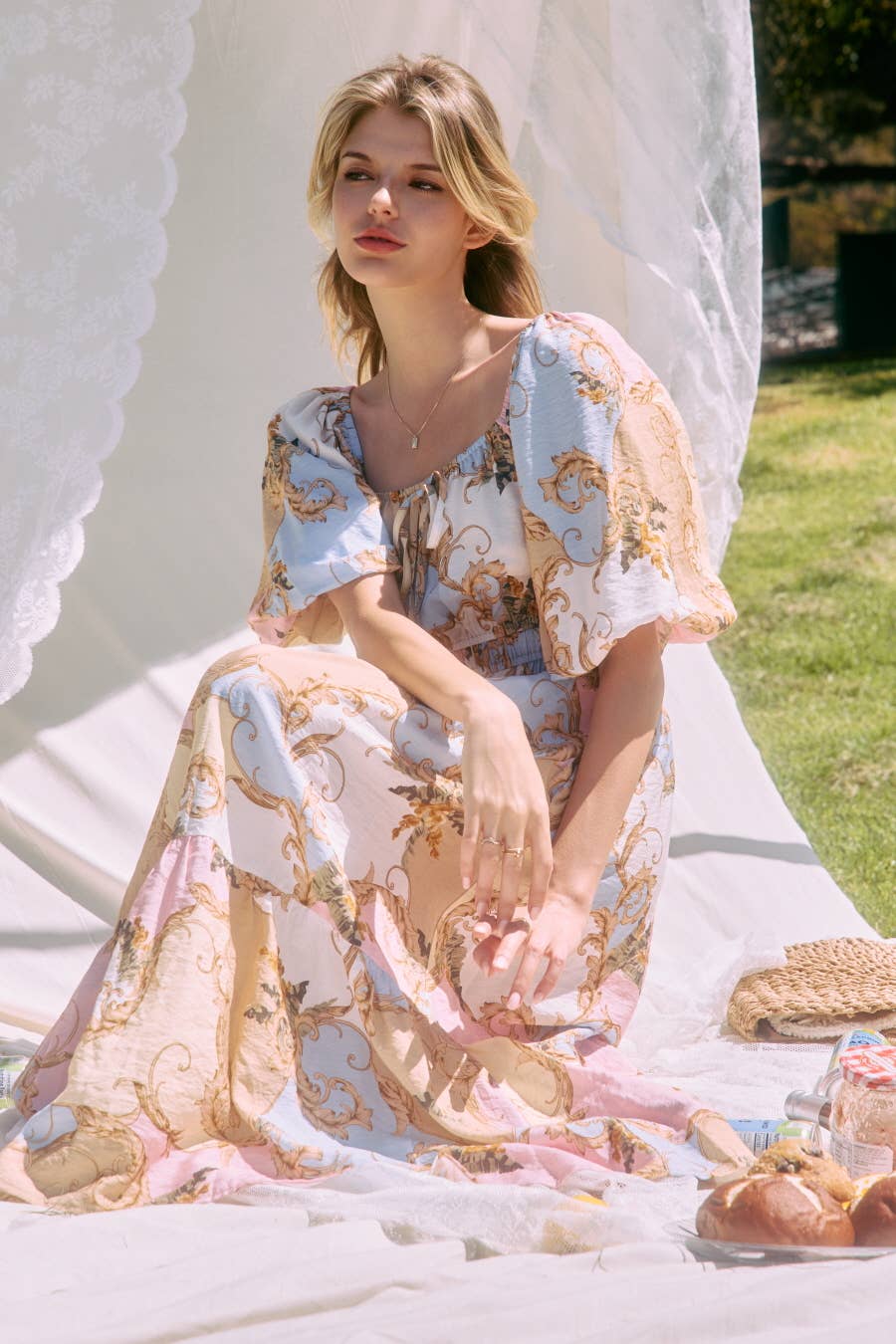 Woman in a floral dress sitting on a white blanket outdoors