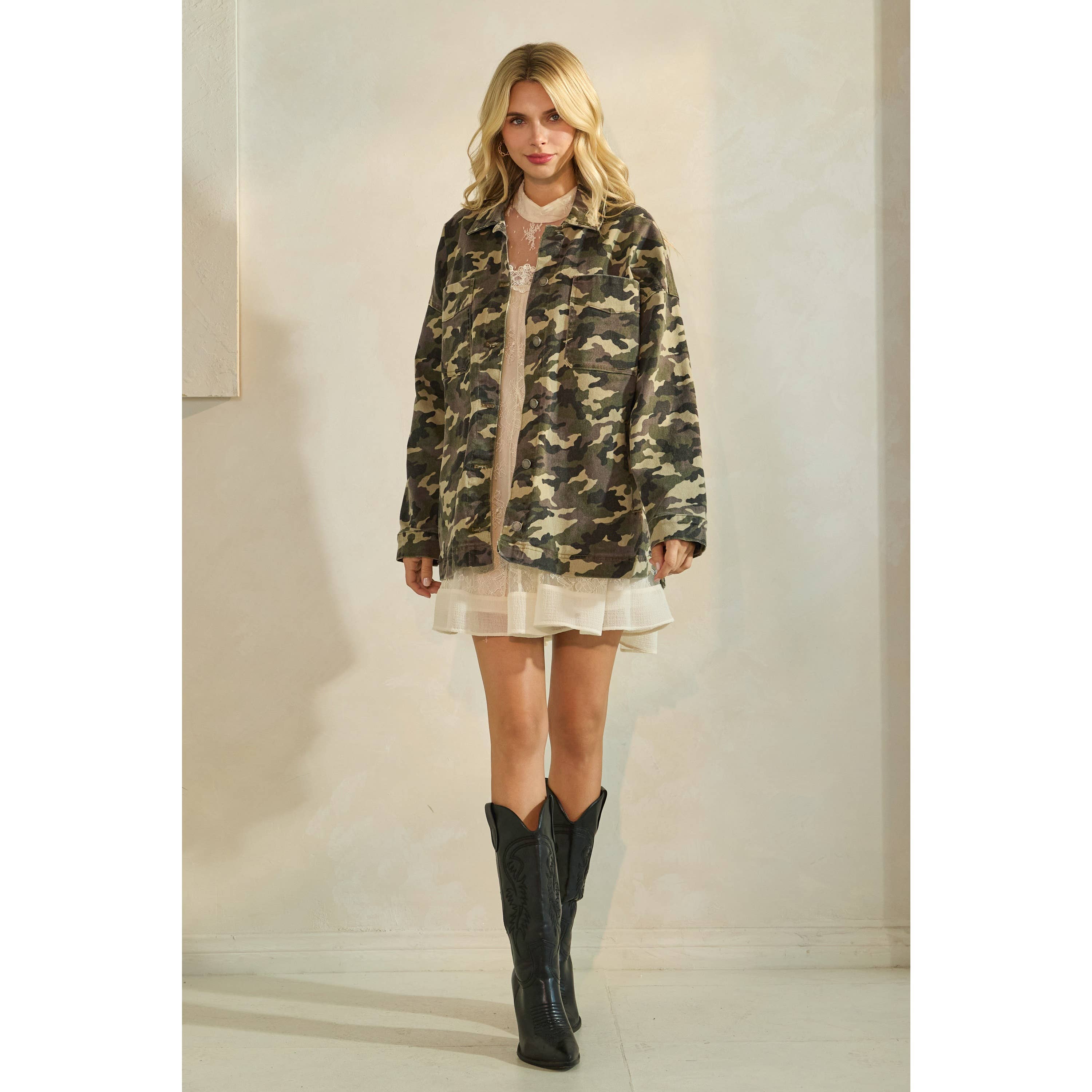 Oversized camouflage print jacket with front pockets and button closure, styled over a white tiered mini dress.
