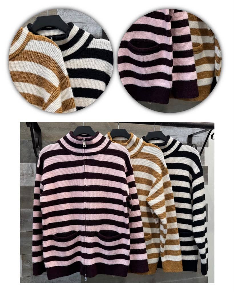 Three striped knit zip-up cardigans hanging on black hangers against a gray wood-paneled wall. The front cardigan is dark purple with pink and white horizontal stripes, while the two behind it show alternate colorways: black and white stripes, and pink and white stripes.