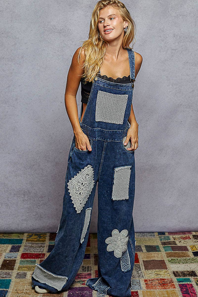 Boho denim patchwork overalls featuring wide legs, crochet lace appliqué patches, and vintage-inspired distressed detailing. Styled with a black crop top and sneakers for a relaxed, eclectic look.”

