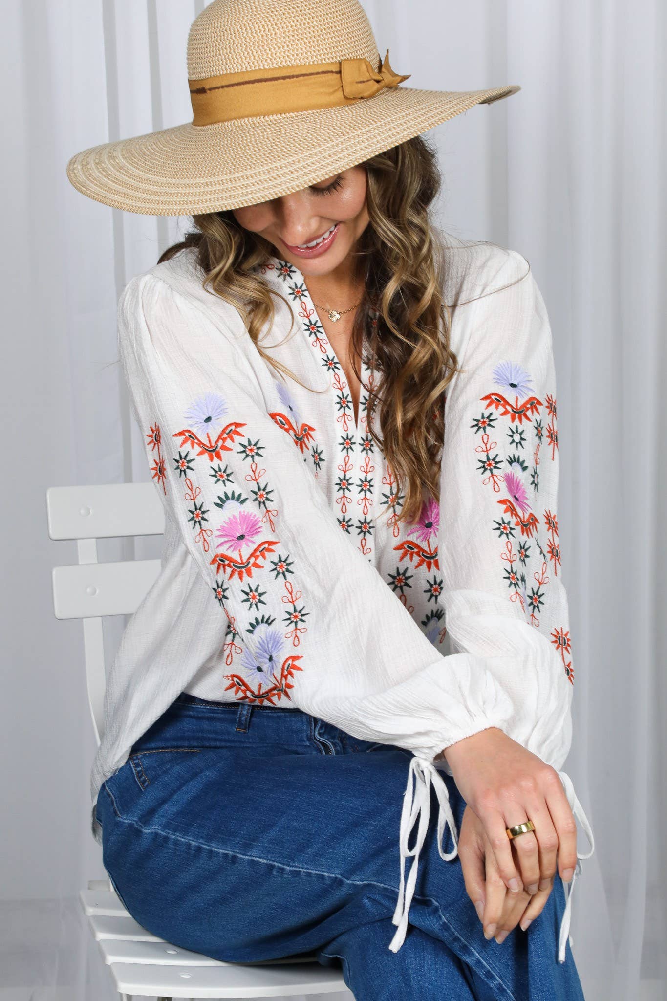 White embroidered peasant blouse with multicolor floral front, split V-neck, and balloon sleeves with ties