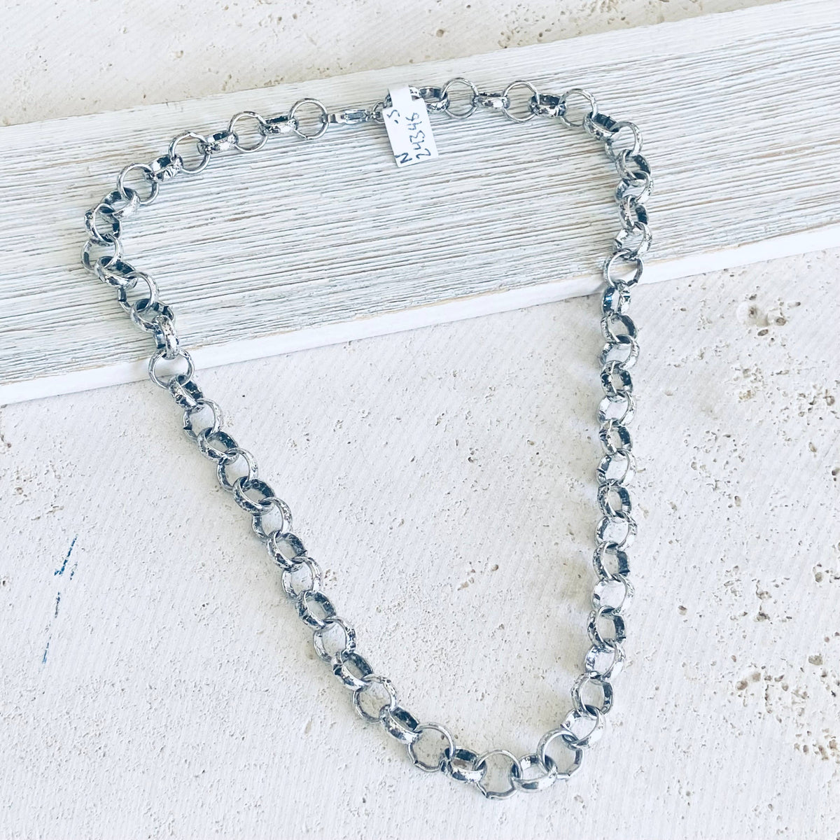 Silver chain necklace on a light wooden surface