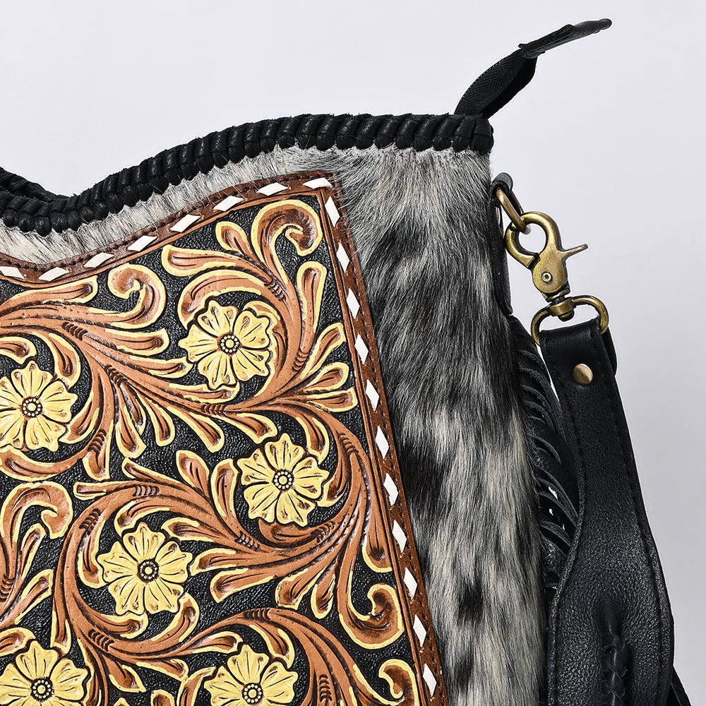 Close-up of a leather bag with intricate floral patterns and fur trim on a light gray background