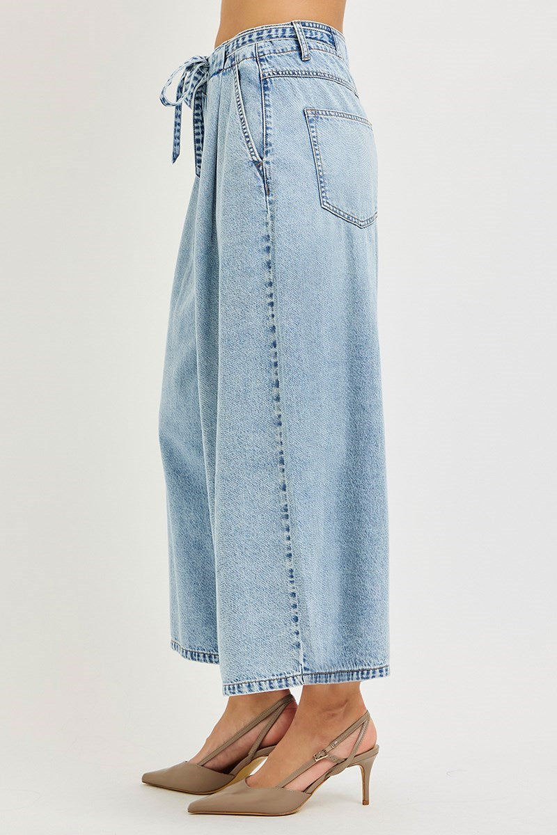 Light blue denim wide-leg pants with a tie waist on a plain background
